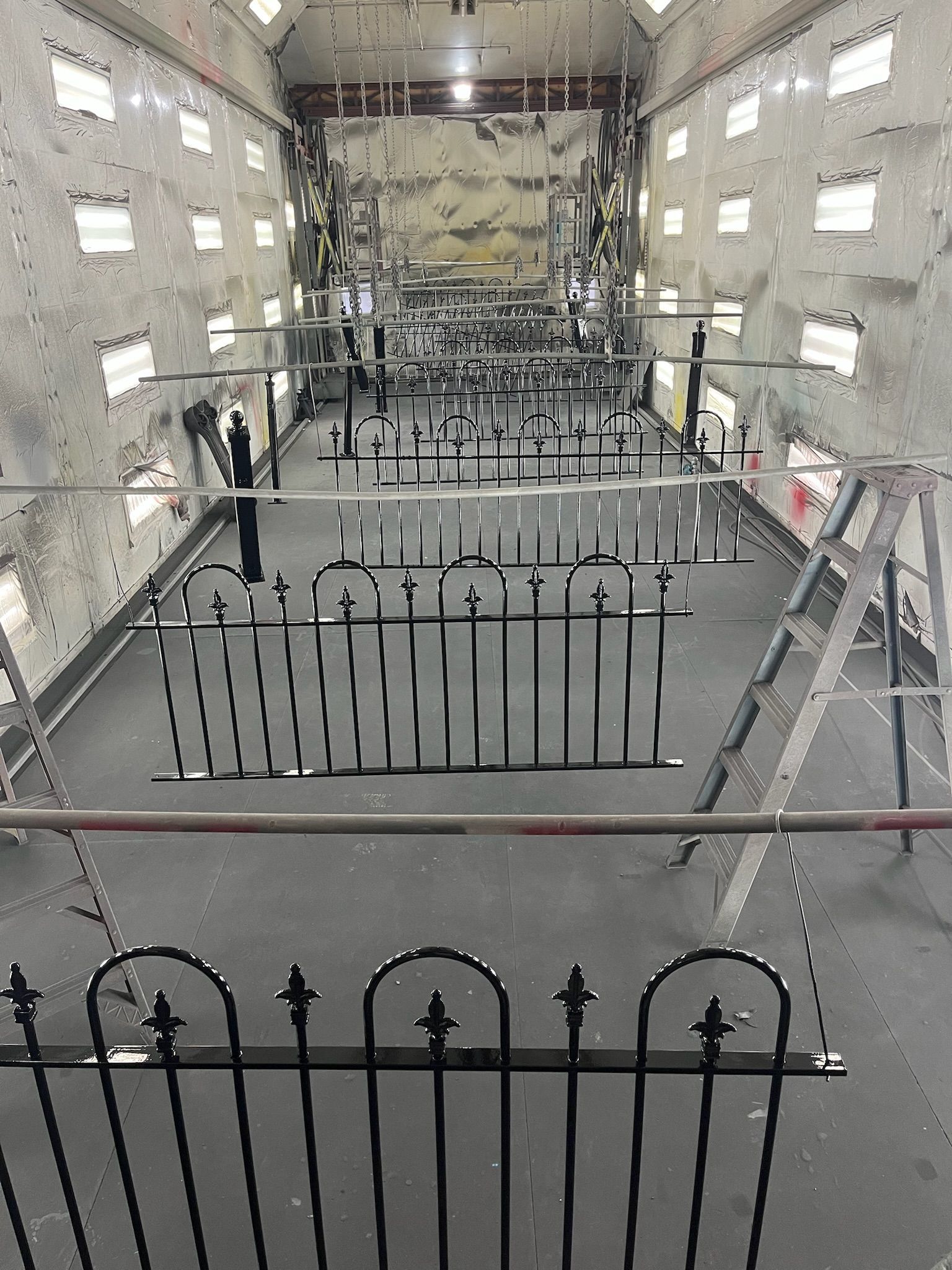 Interior view of a building under renovation, with black iron fences, scaffolding, and many windows.