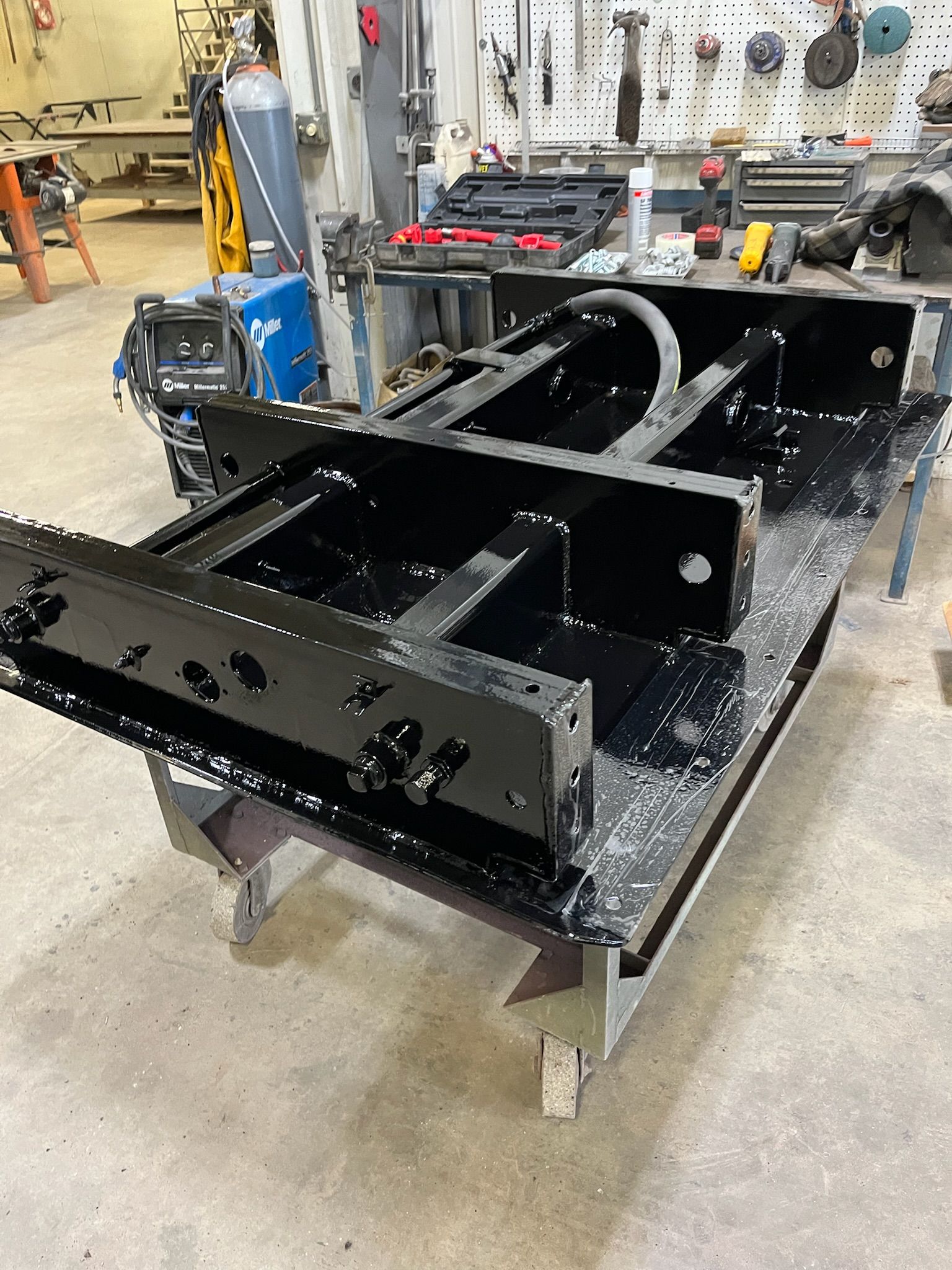Black metal frame assembly on a metal workbench in a workshop.