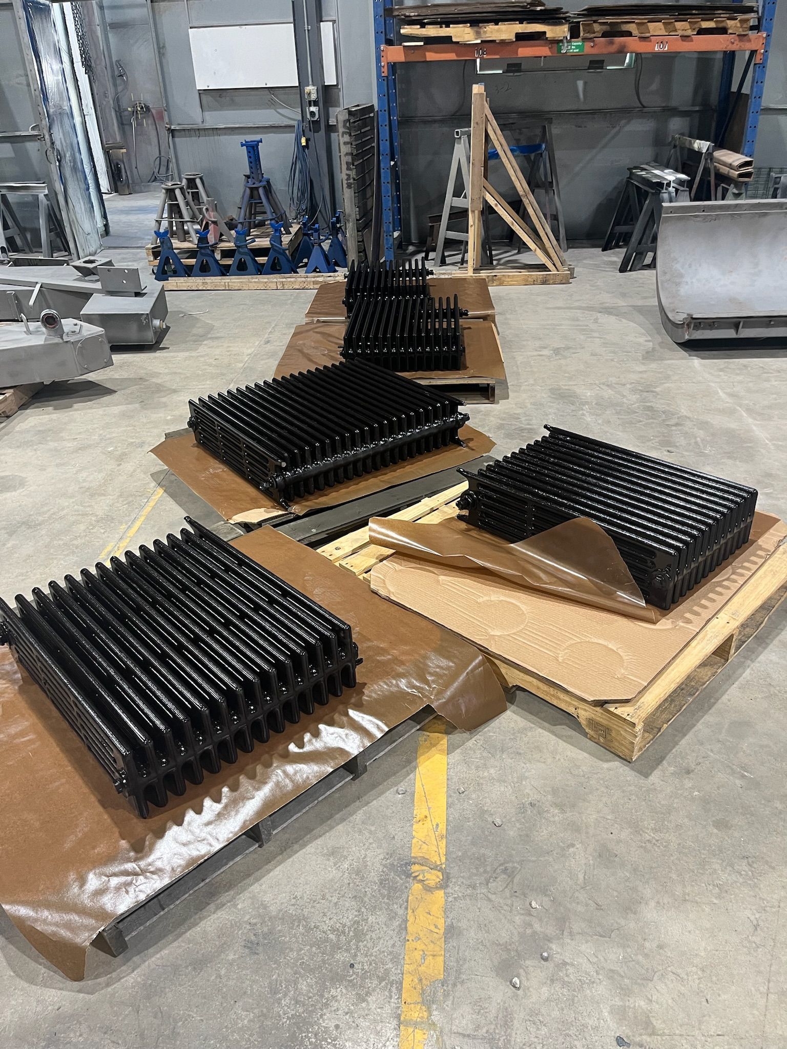 Several black, industrial components on cardboard, likely in a warehouse or factory setting.