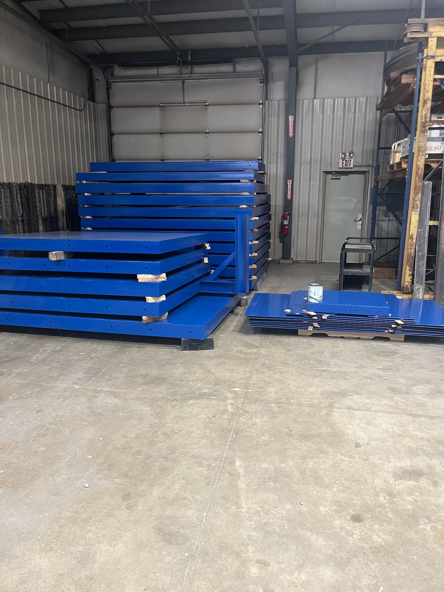 Stacks of blue metal sheets in a warehouse setting.