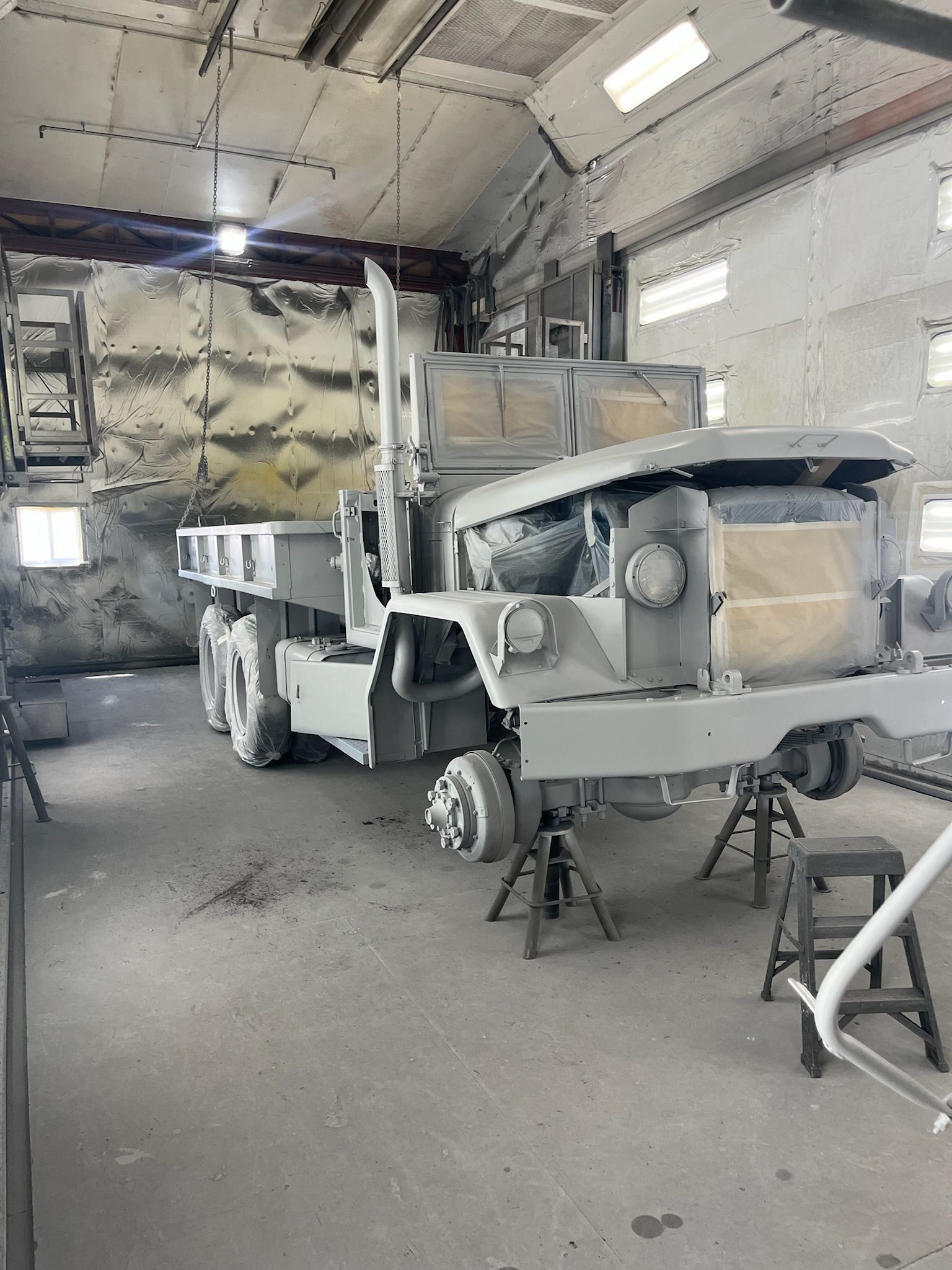 Truck in a workshop being painted with gray primer.