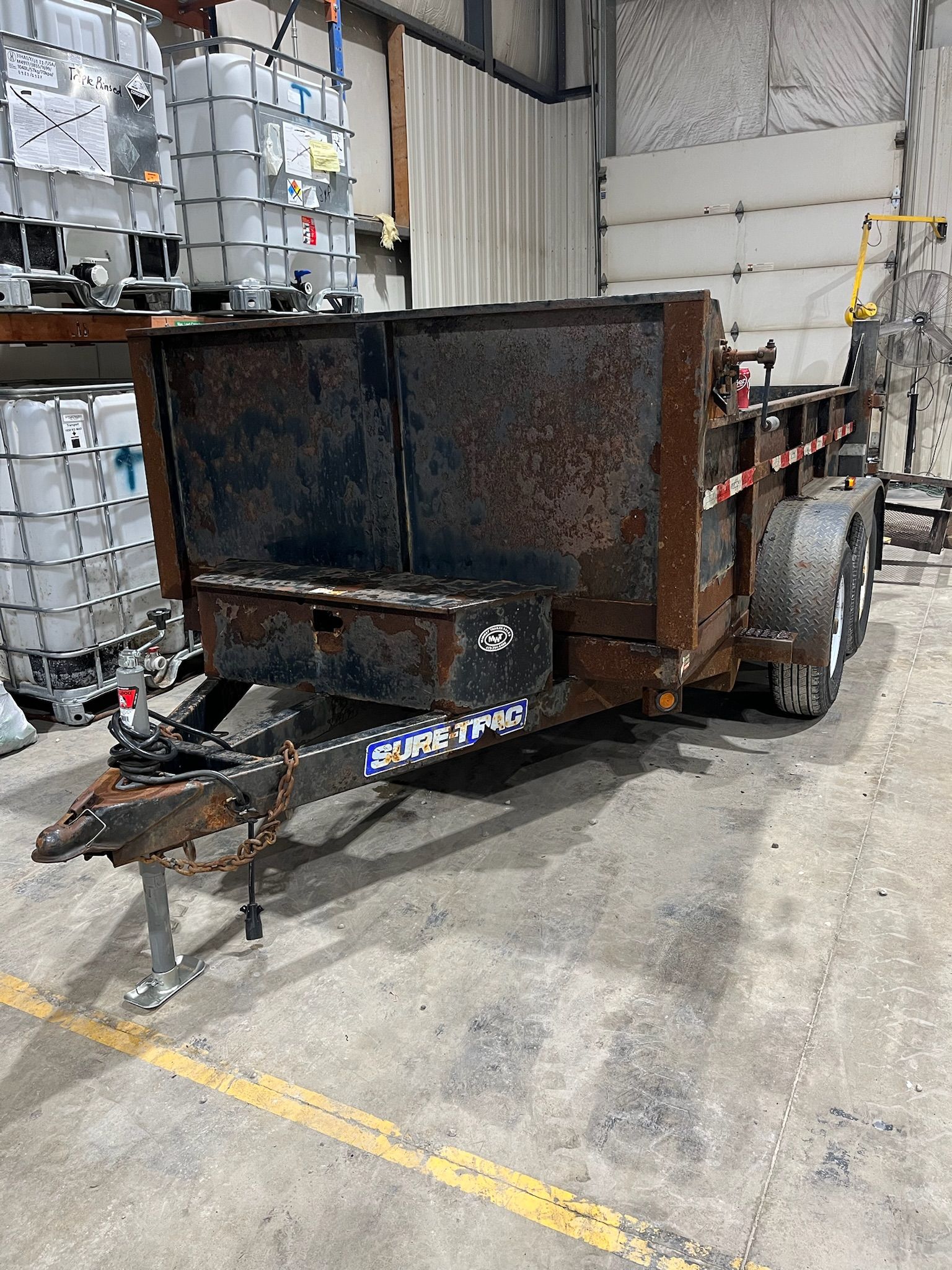 Rusty dump trailer in a warehouse setting.