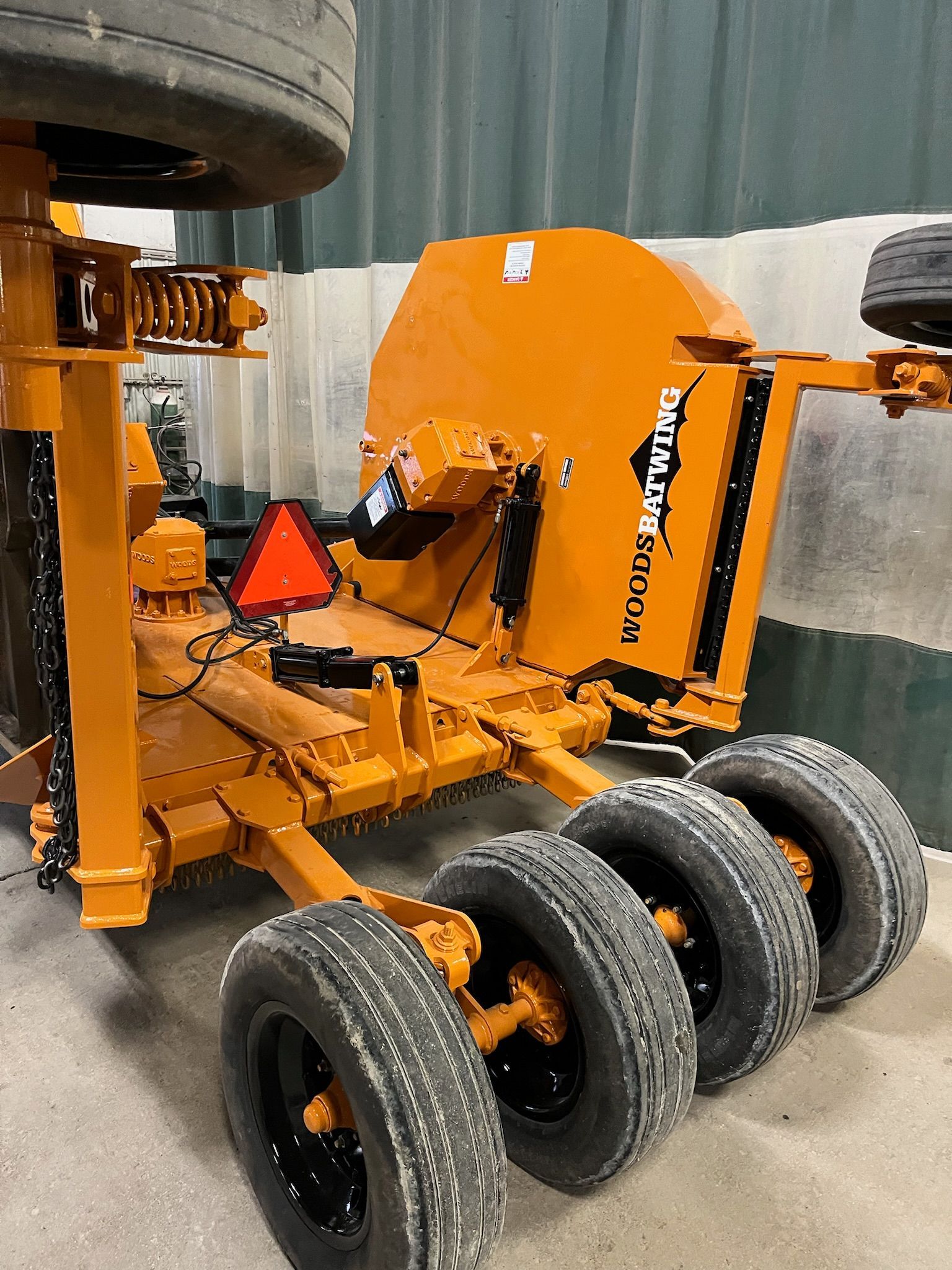 Orange road grader with four tires and a black tire on top. Red triangle visible.