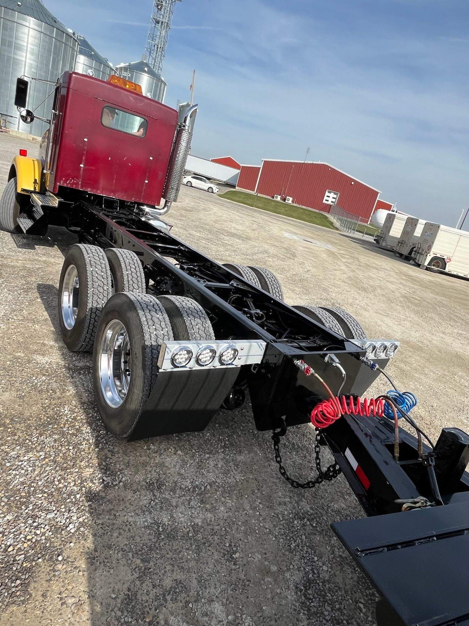 Red semi-truck cab with a black chassis; parked outdoors.