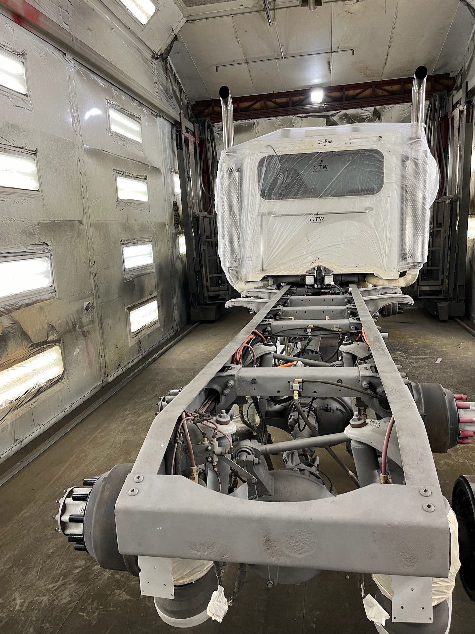 Truck chassis inside a spray booth, ready for painting.