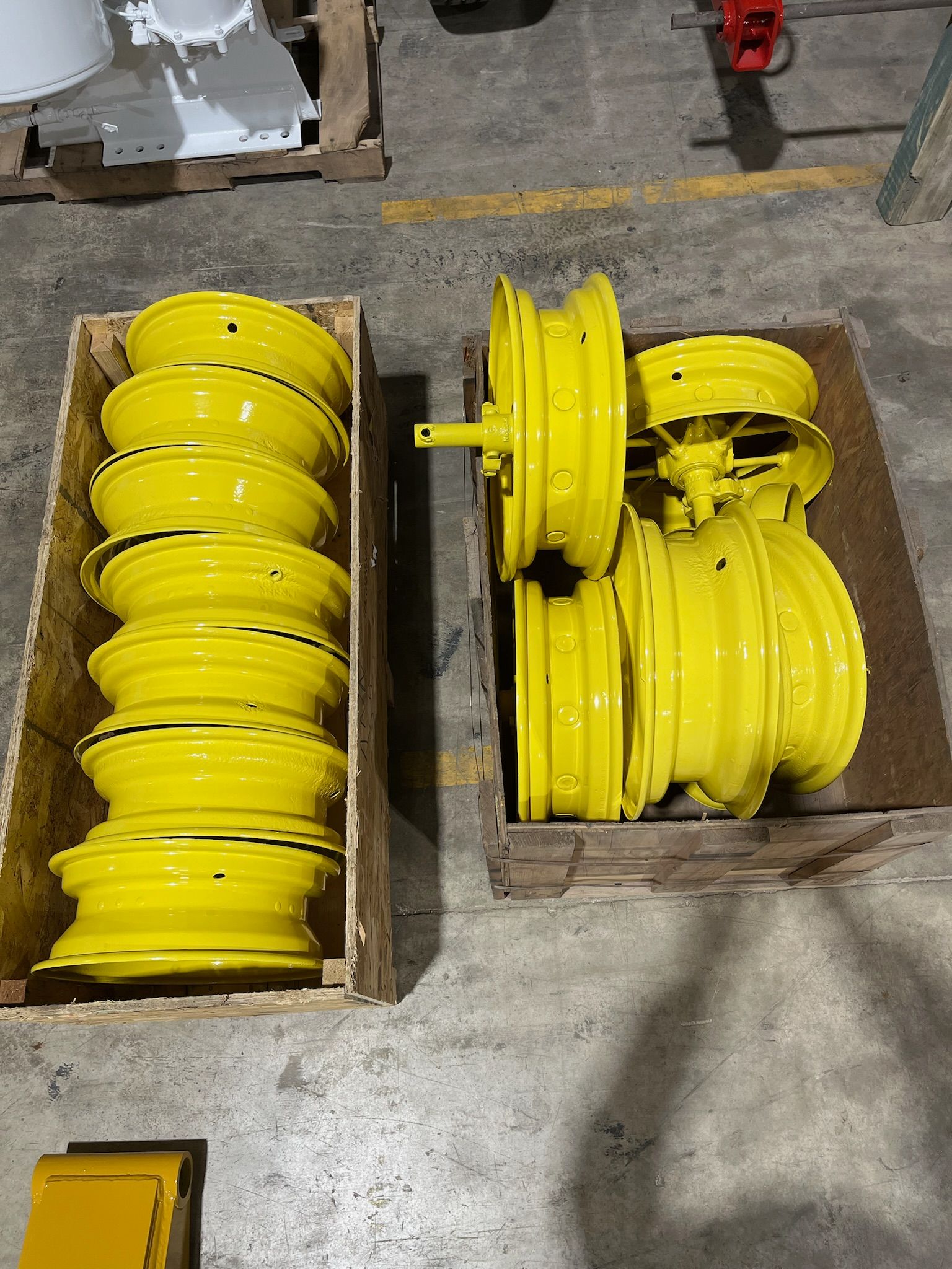 Two wooden crates holding several new, yellow tractor wheels.