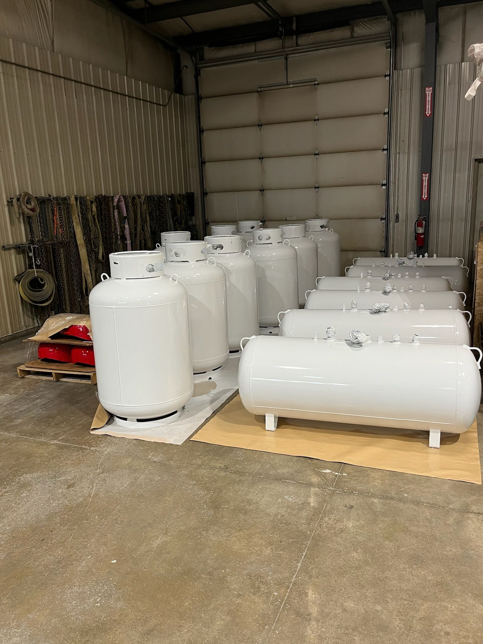 White propane tanks in a warehouse, stacked and lined up.