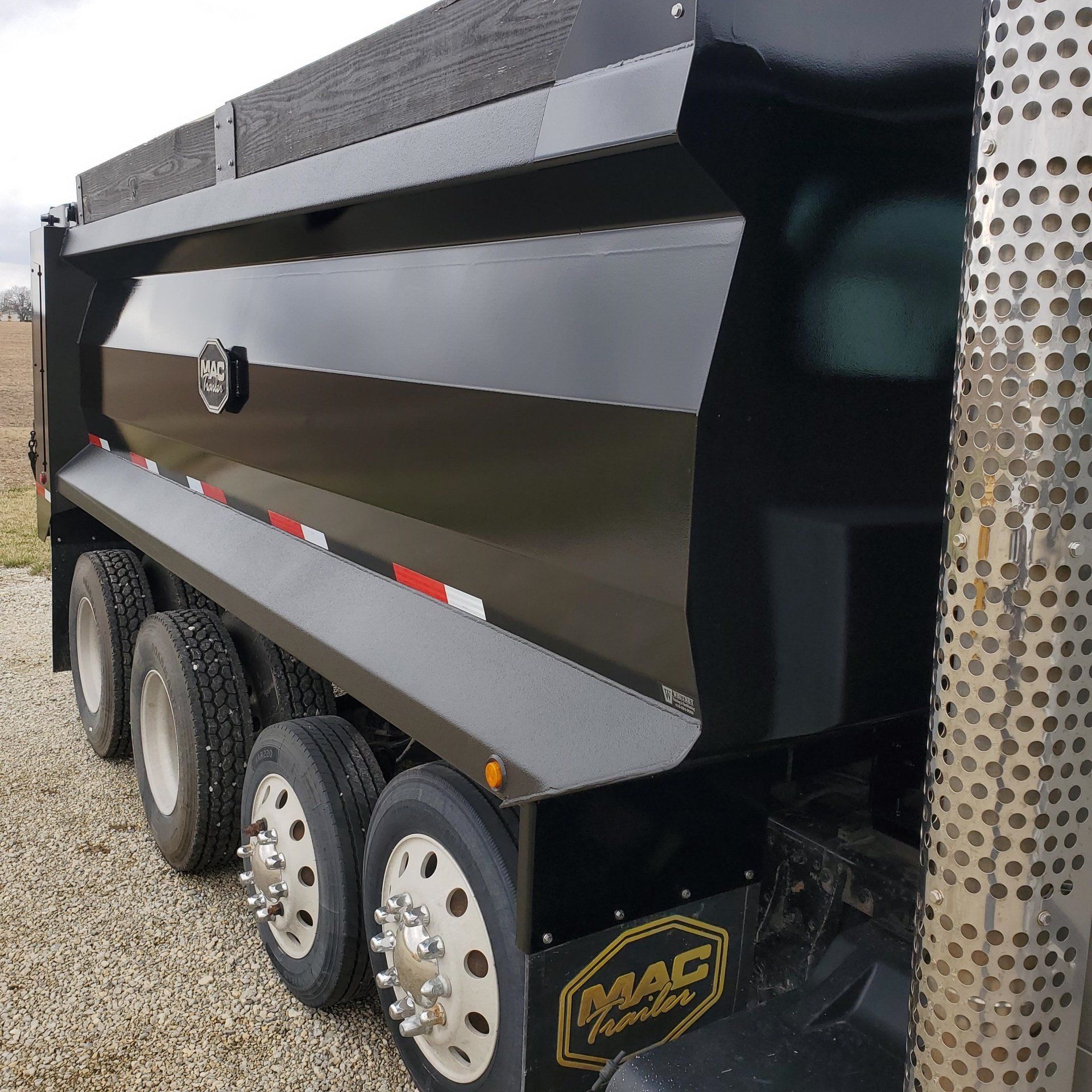 Black dump truck with multiple wheels, MAC trailer logo.