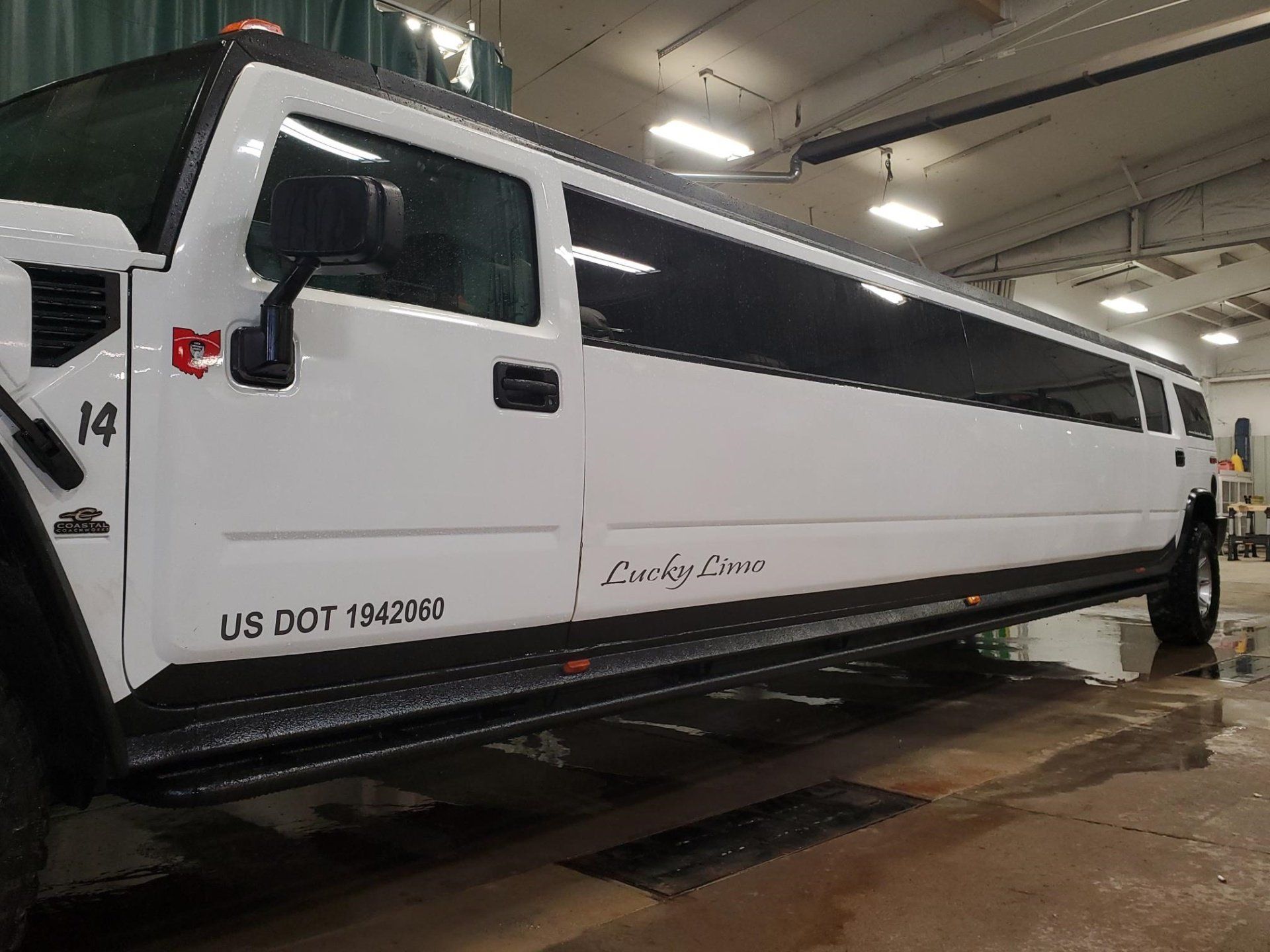 White Hummer limousine with tinted windows parked in a garage.