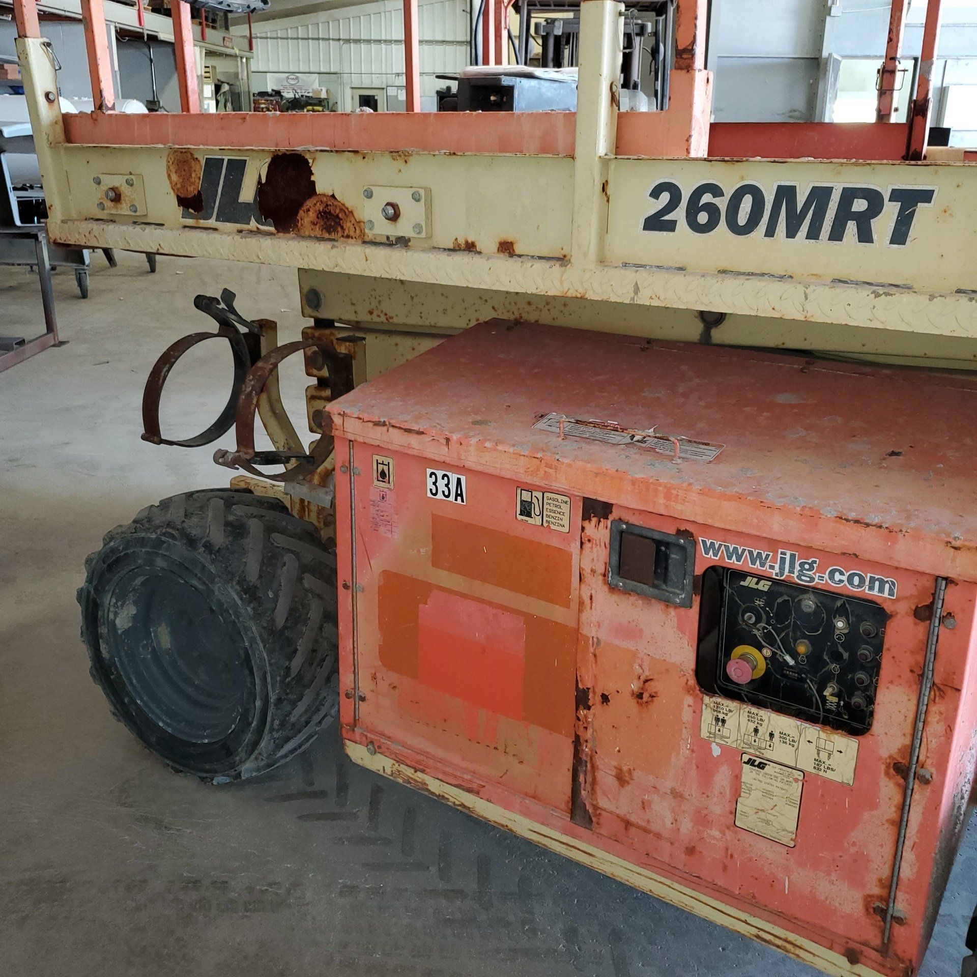 Orange and beige JLG 260MRT lift in a warehouse setting, showing control panel and tire.