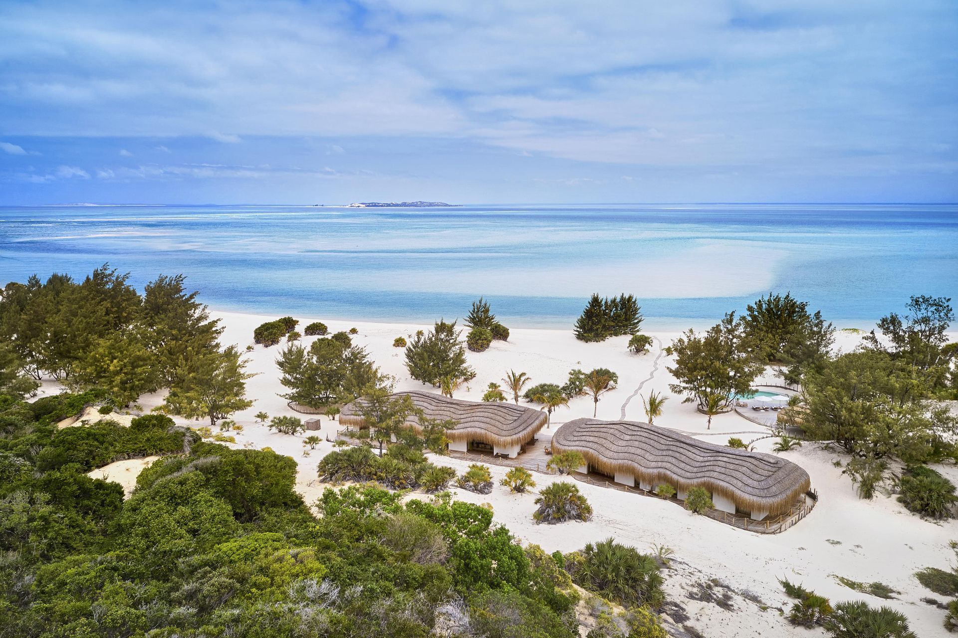 An aerial view of a beach with a lot of trees and buildings near the ocean.