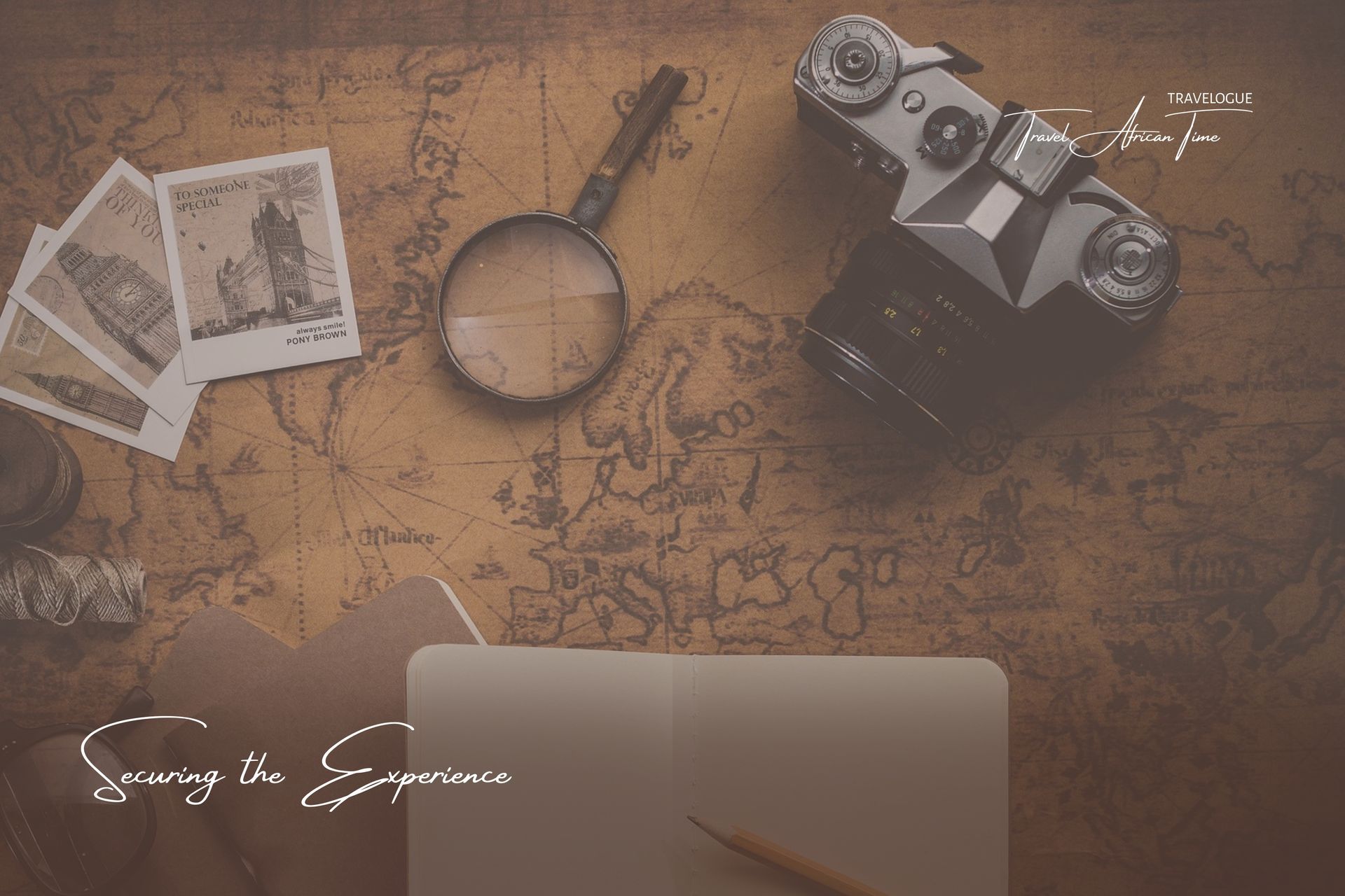 An overhead view of a vintage map, a camera, a magnifying glass, some photographs, and an open notebook with a pen.