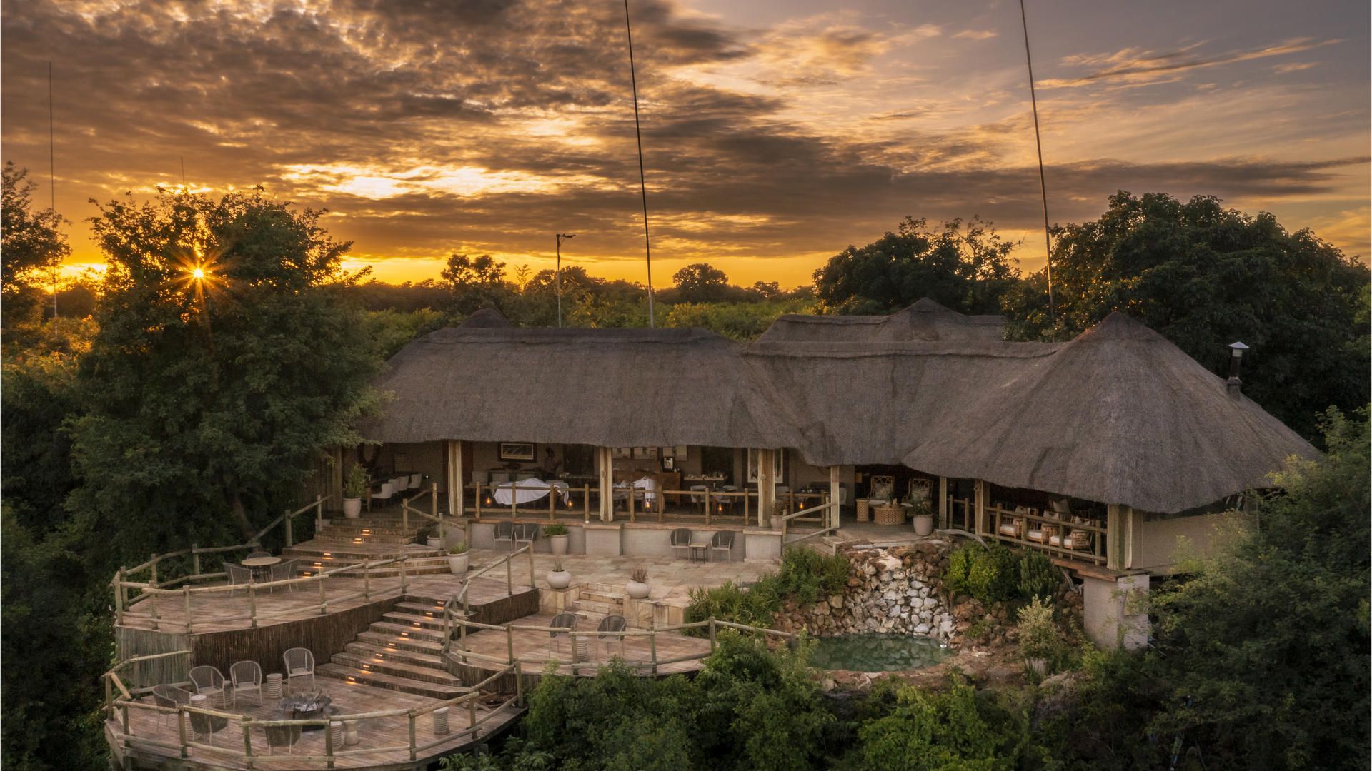 An aerial view of a thatched roofed building at sunset