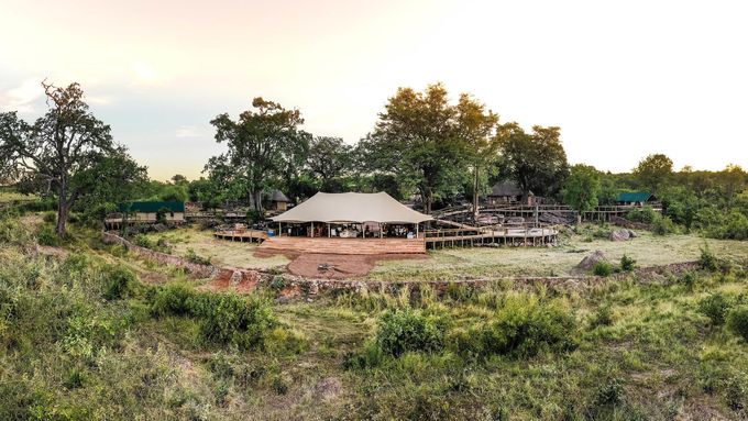 An aerial view of a tent in the middle of a field surrounded by trees.