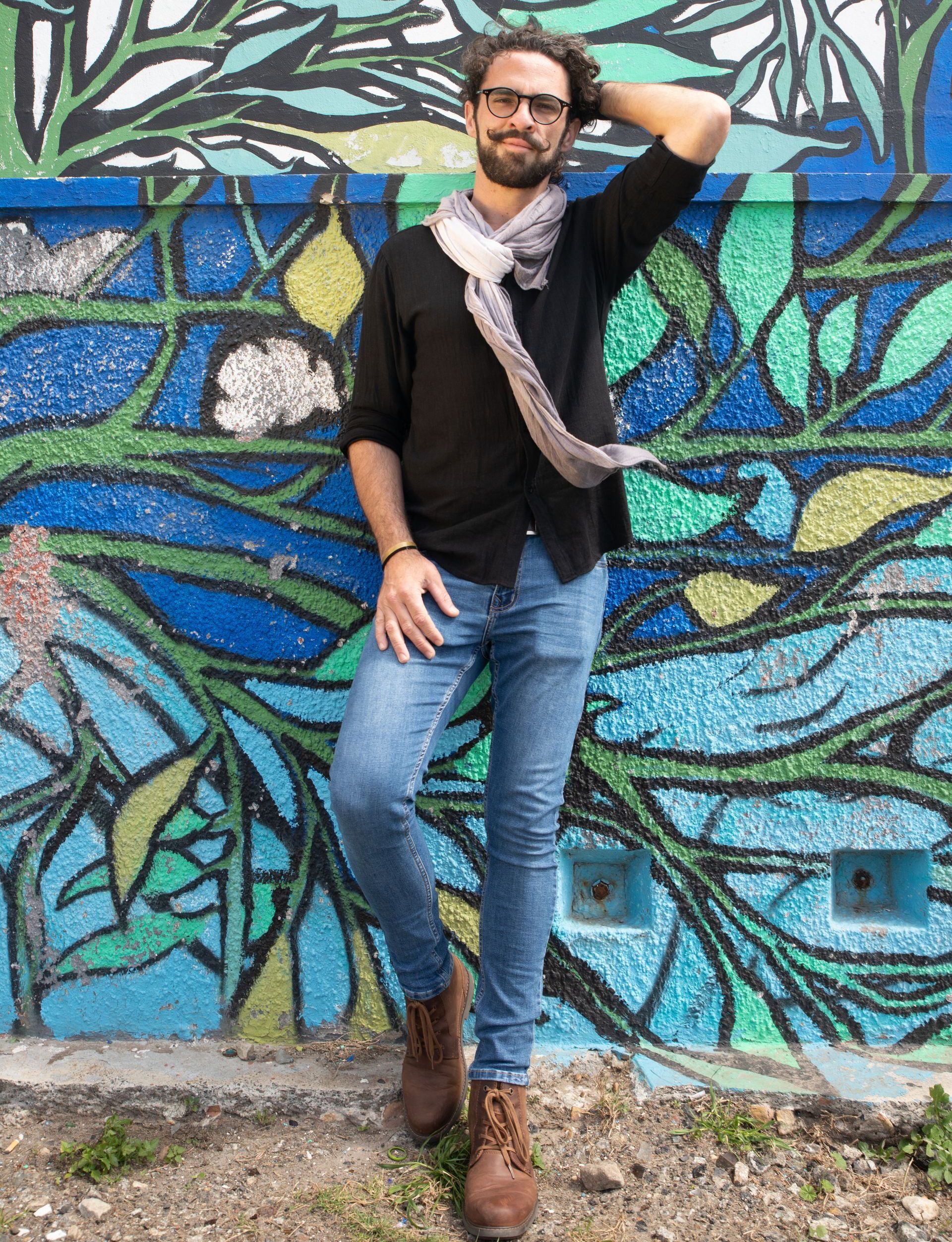 A man is standing in front of a colorful mural on a wall.