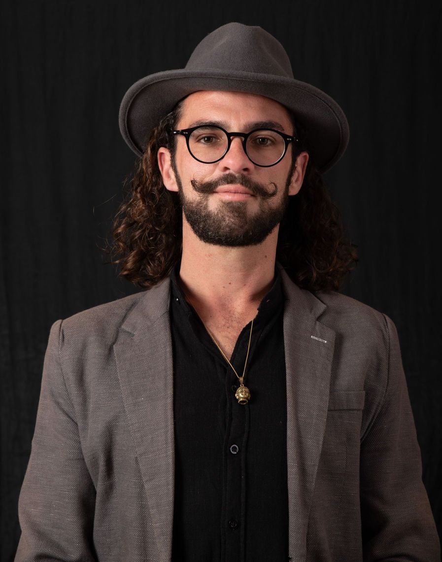 A man with long hair and a beard wearing a hat and glasses.