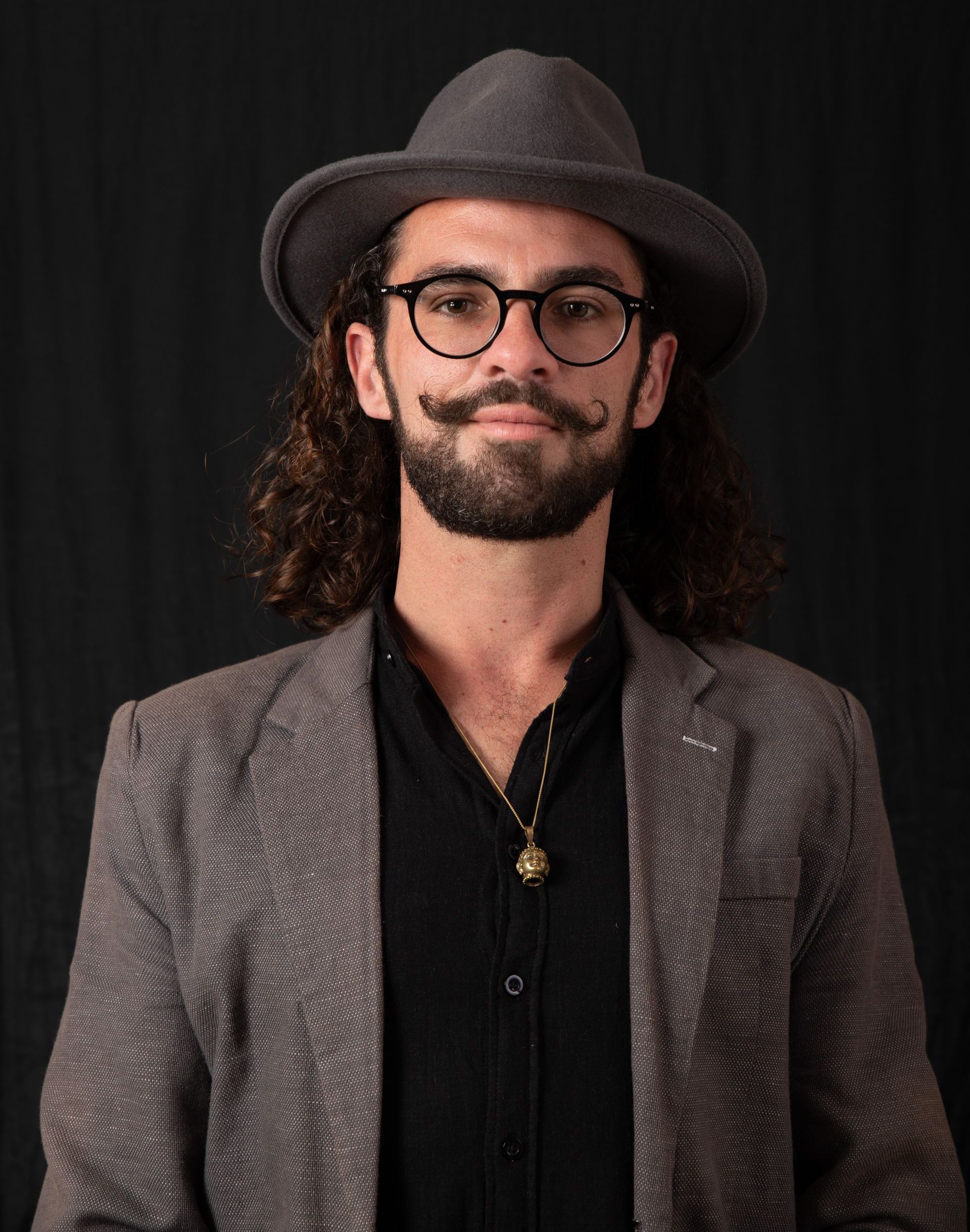 A man with long hair and a beard wearing a hat and glasses.