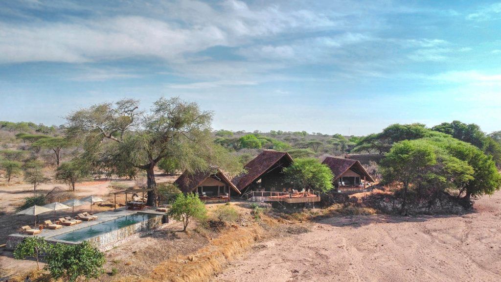 An aerial view of a lodge with a swimming pool in the middle of the desert.