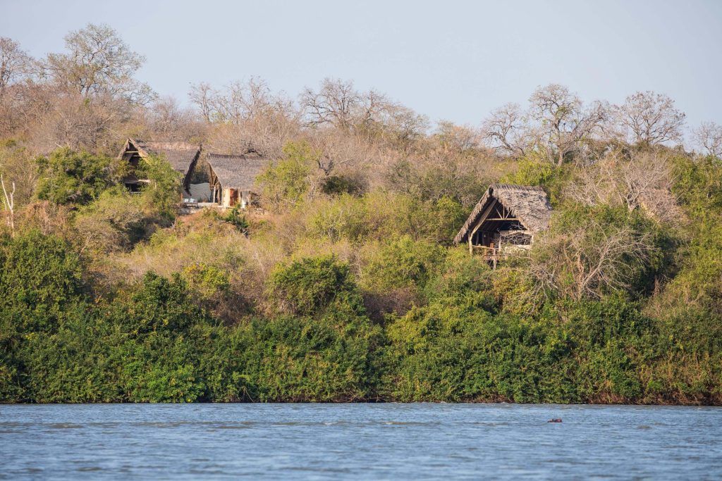 A couple of houses on top of a hill next to a body of water.