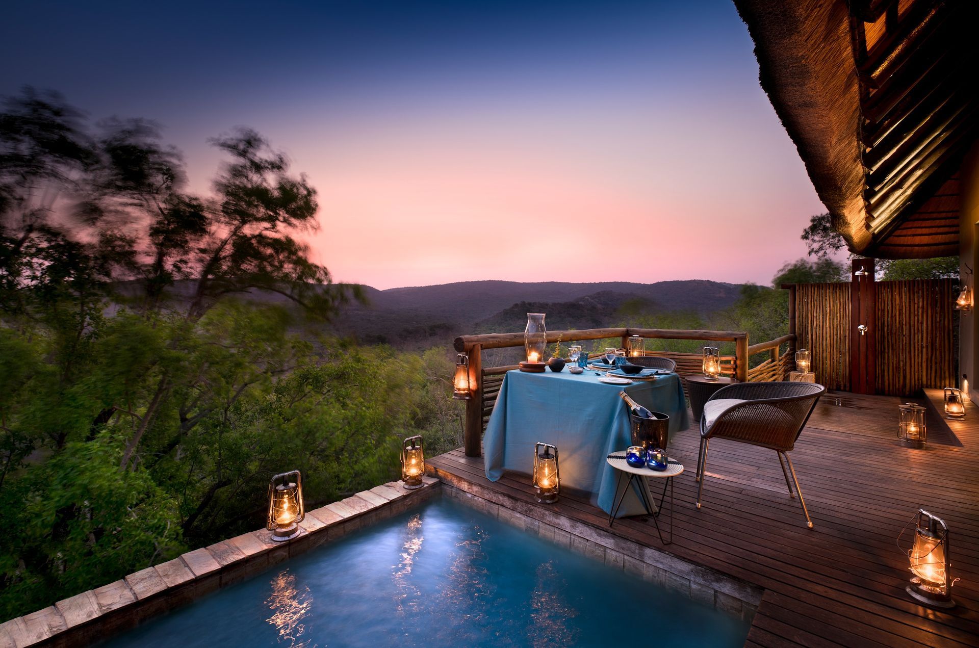 A swimming pool with a table and lanterns around it