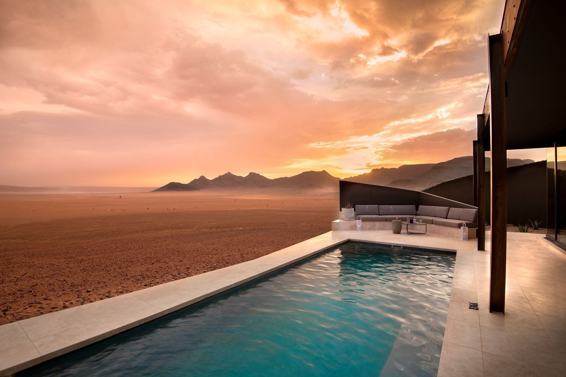 A swimming pool with a view of the desert at sunset.