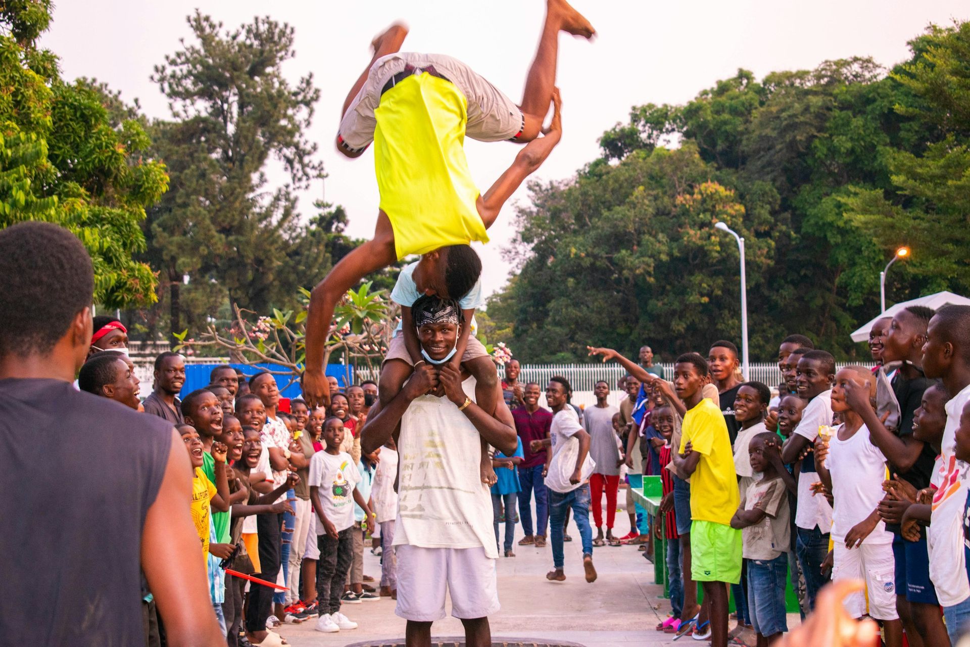 A man is doing a handstand on a man 's shoulders in front of a crowd.