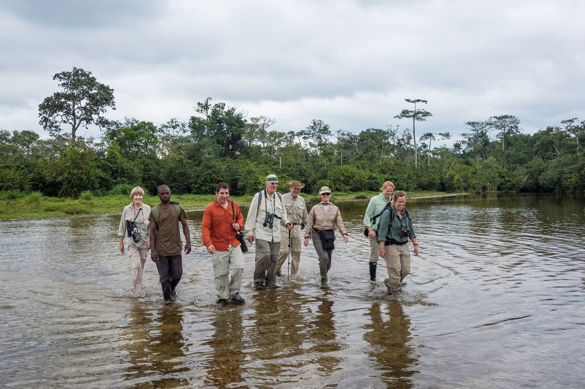 A group of people are walking through a muddy river