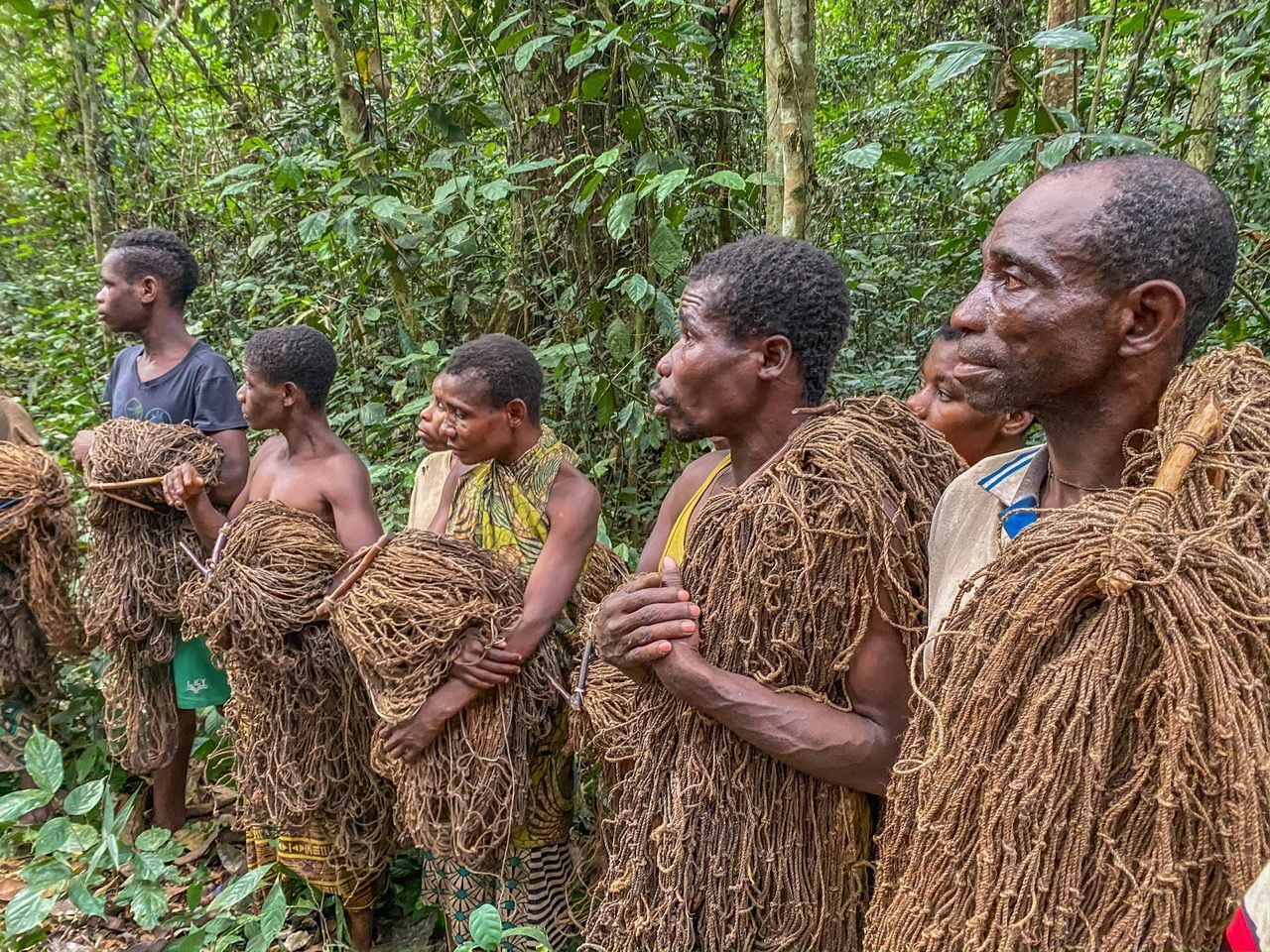 A group of men are standing in a line in the woods.