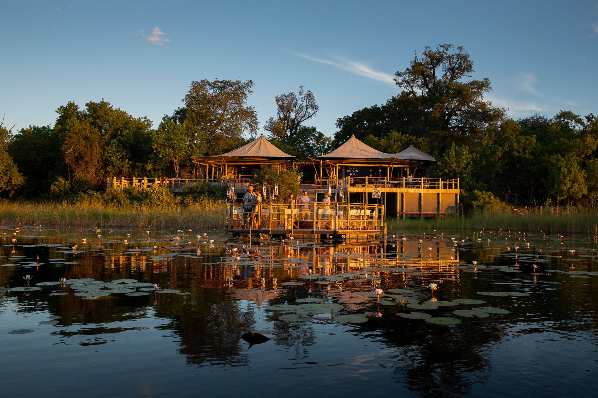 A house is sitting on a dock in the middle of a lake surrounded by trees.