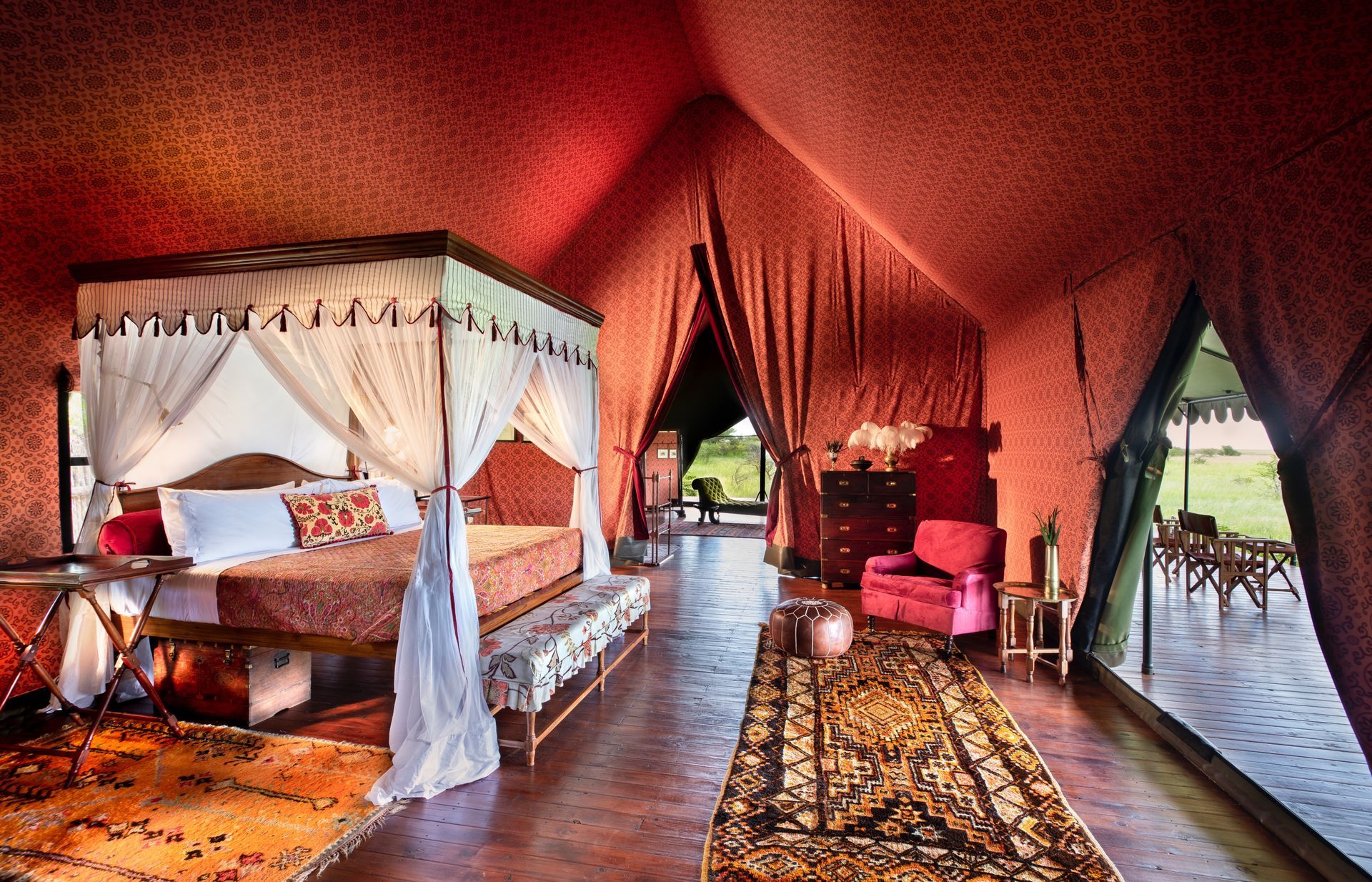 A bedroom in a tent with a canopy bed and a rug.