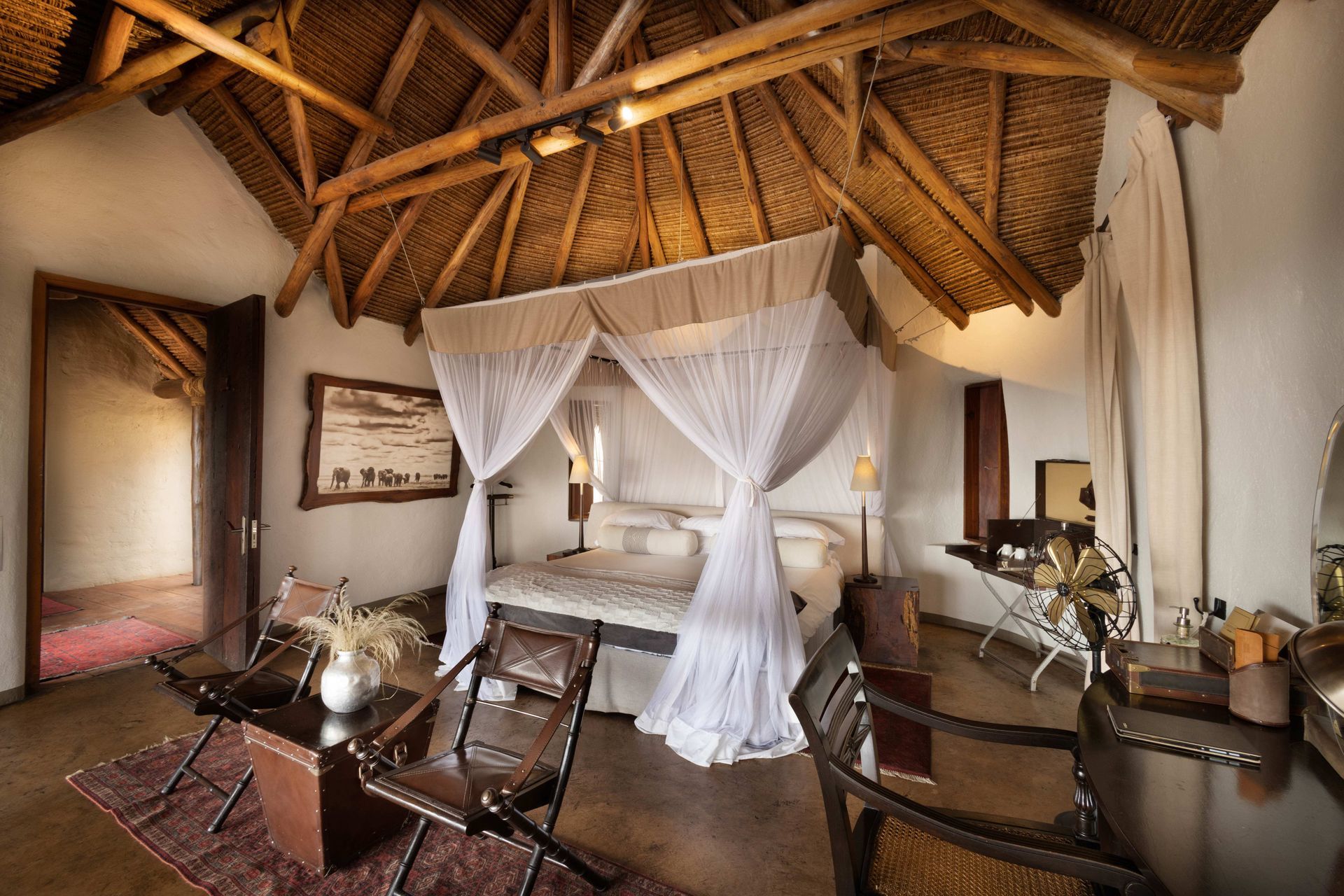 A bedroom with a canopy bed and a thatched roof