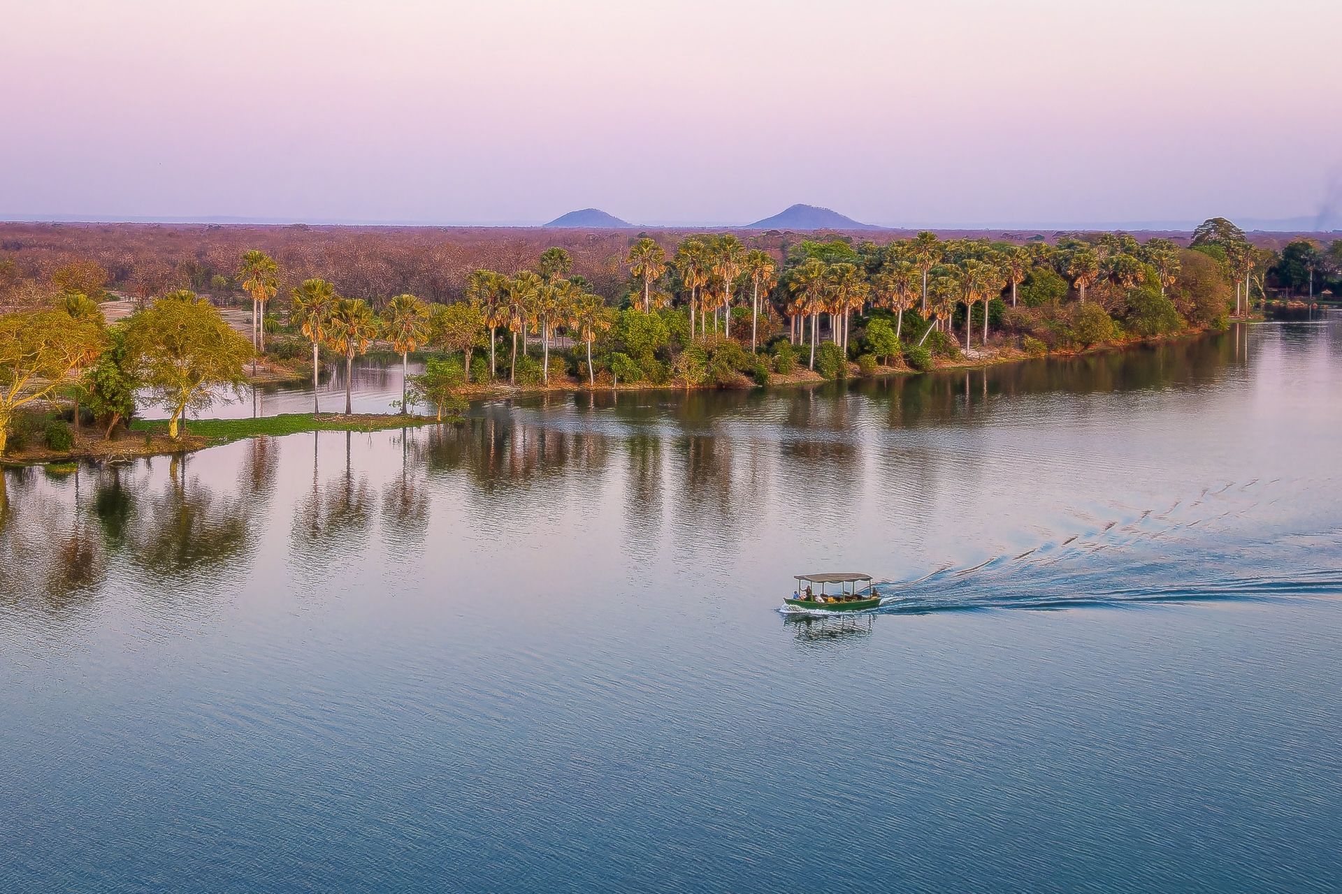 A boat is floating on top of a large body of water surrounded by trees.