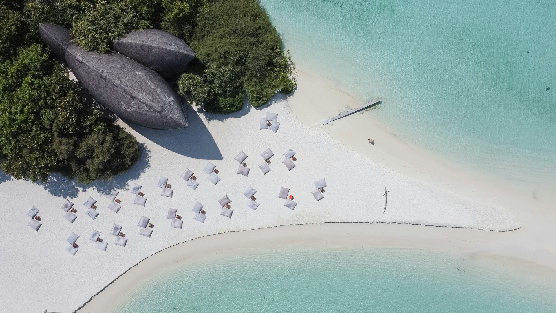 An aerial view of a beach with umbrellas and boats in the water