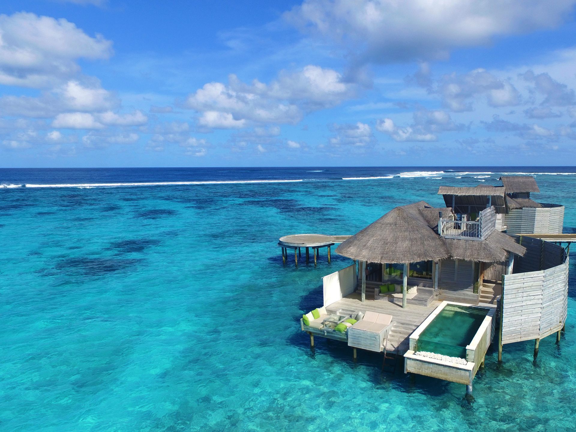 An aerial view of a small house in the middle of the ocean.