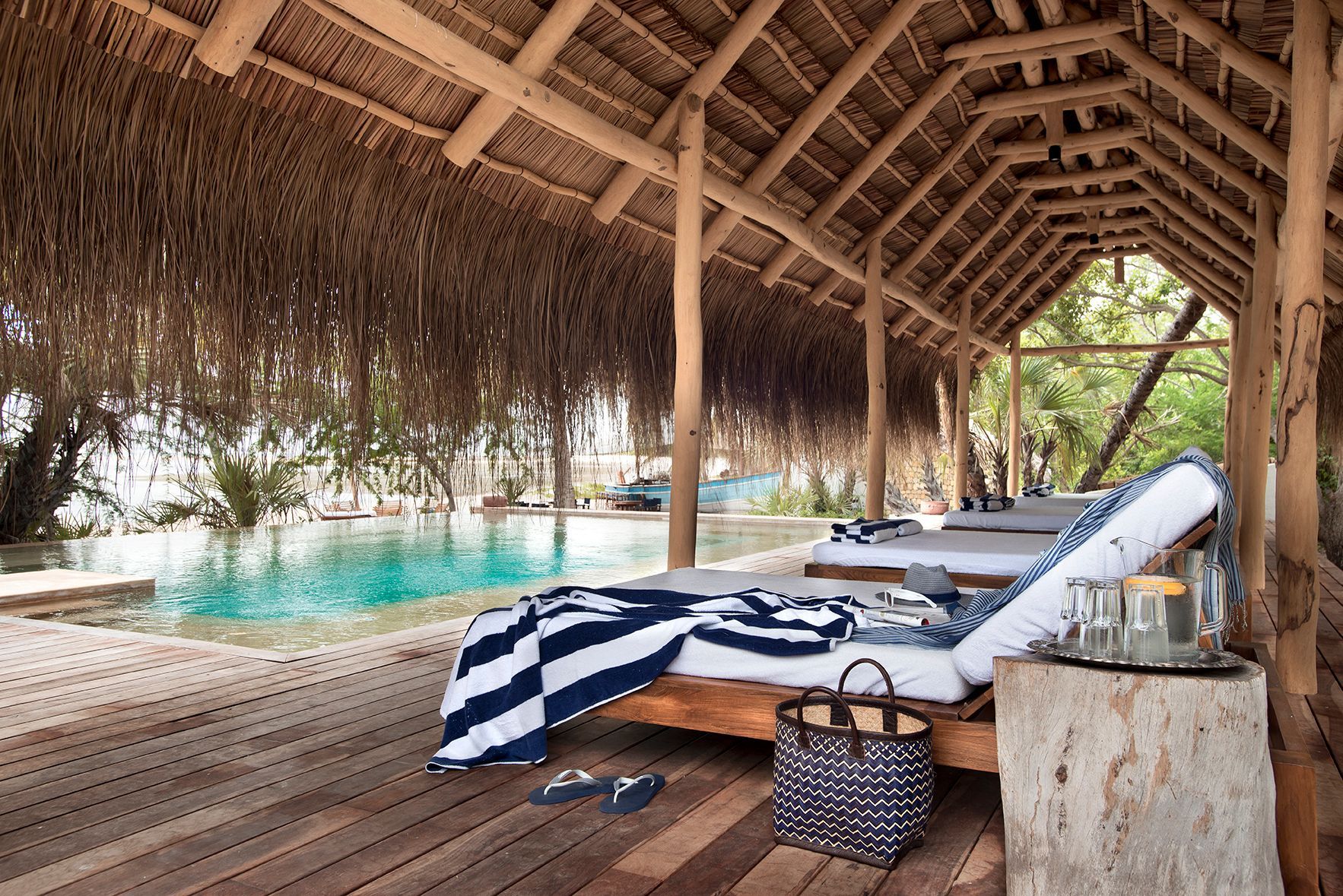 A thatched hut with a swimming pool in the background