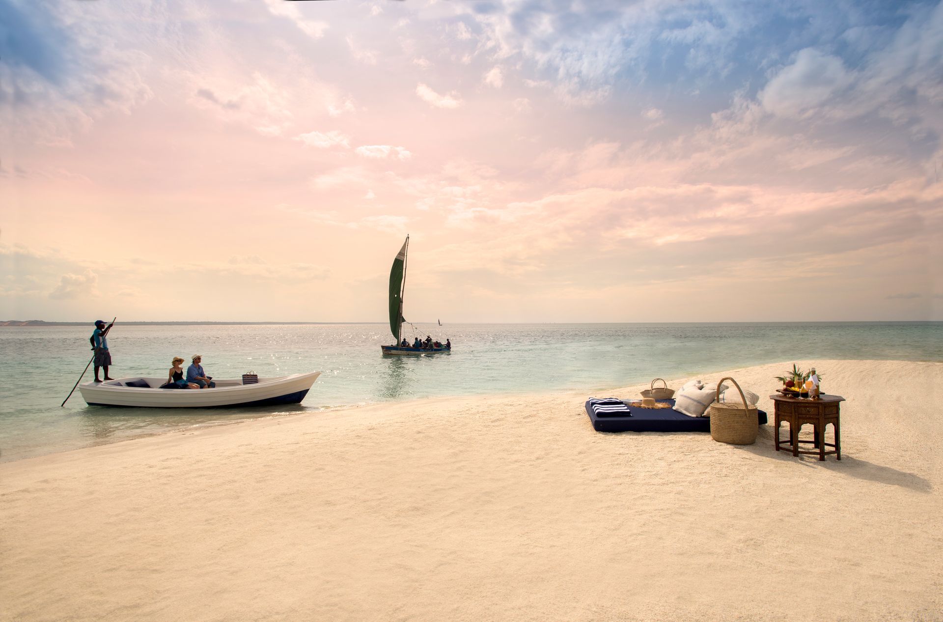 A boat is docked on a sandy beach next to a sailboat.