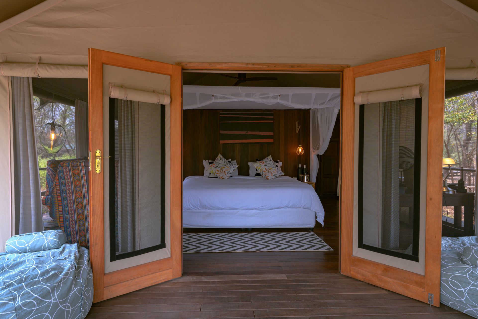 There is a bed in the middle of the room with the doors open.