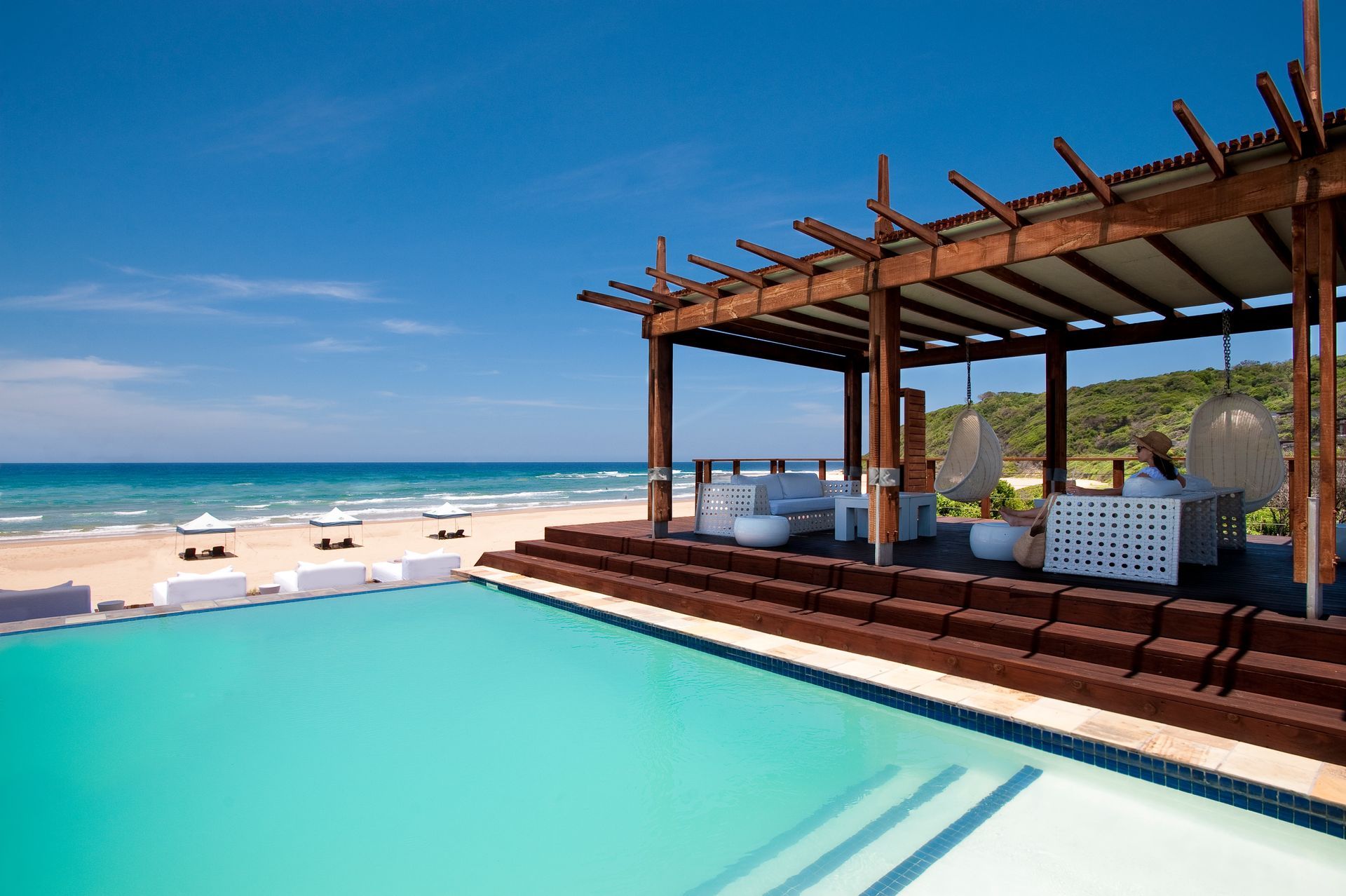 A swimming pool with a pergola overlooking the ocean