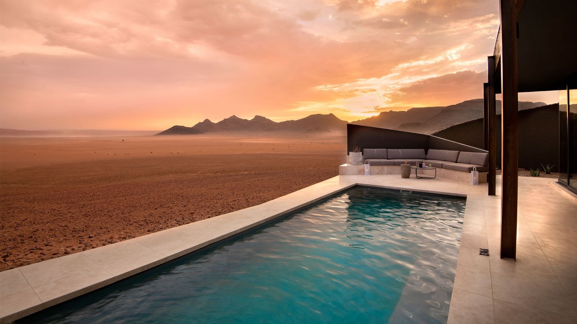 A swimming pool with a view of the desert at sunset.