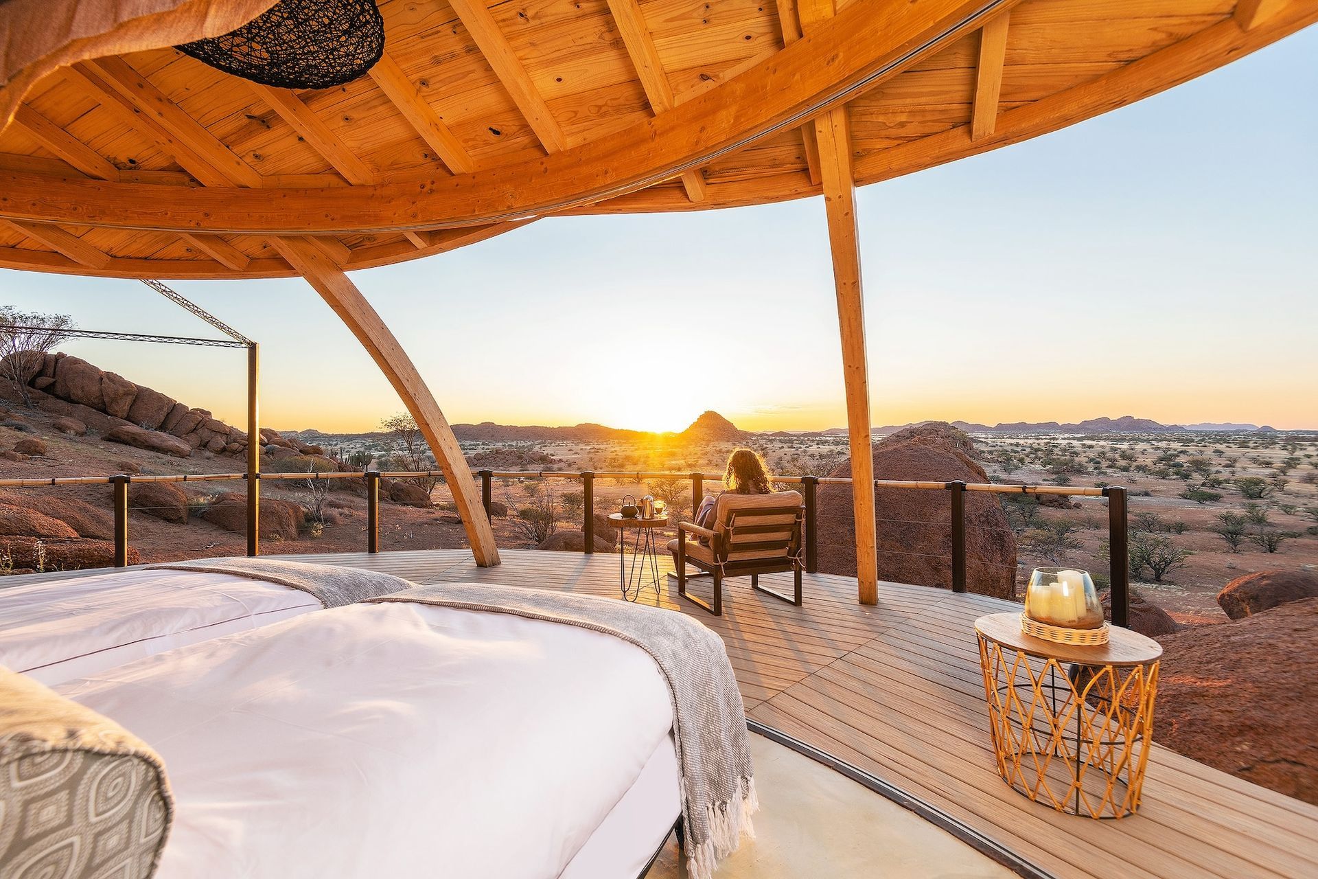A woman is sitting on a chair on a deck overlooking the desert.
