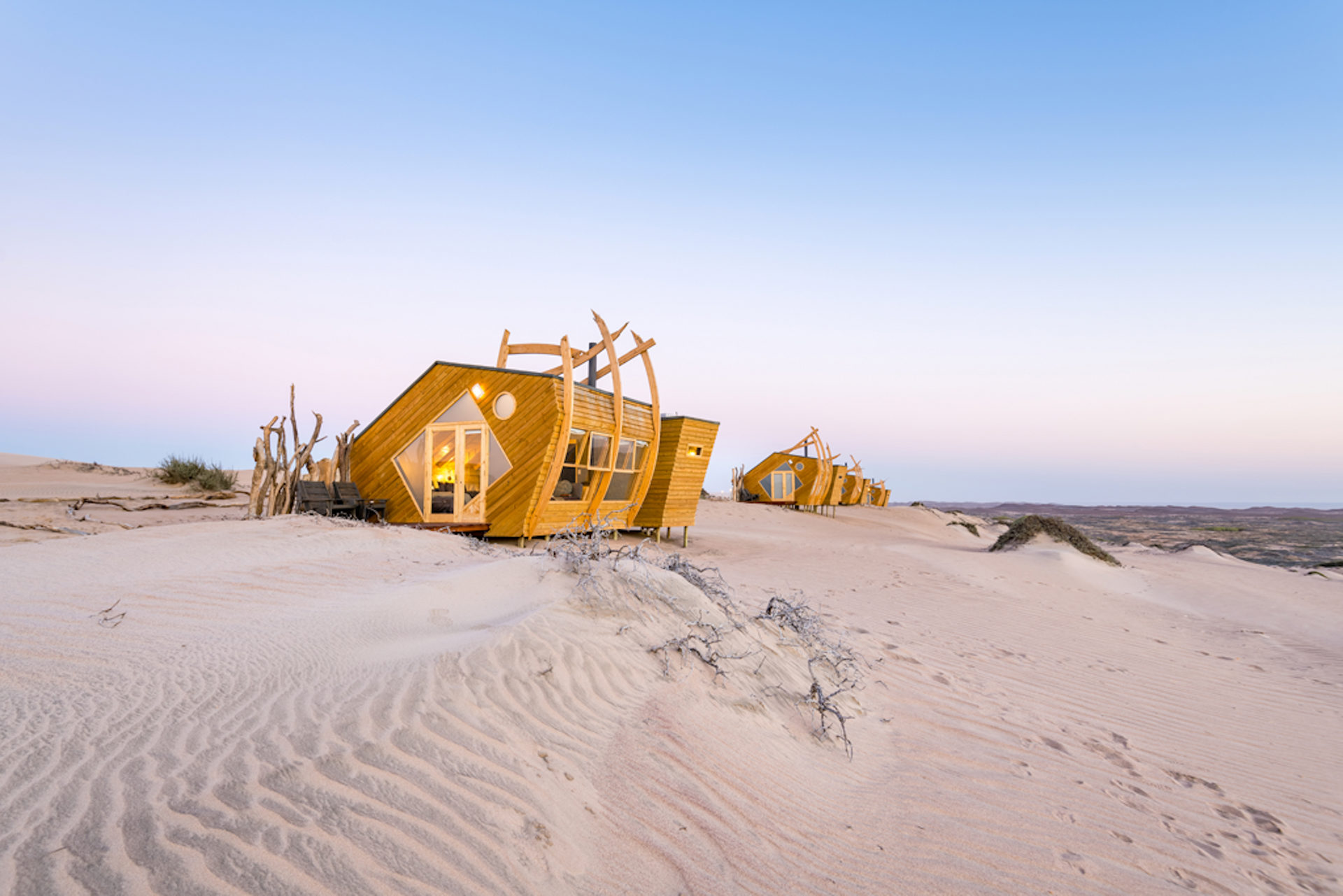 A group of yellow houses are sitting on top of a sand dune.