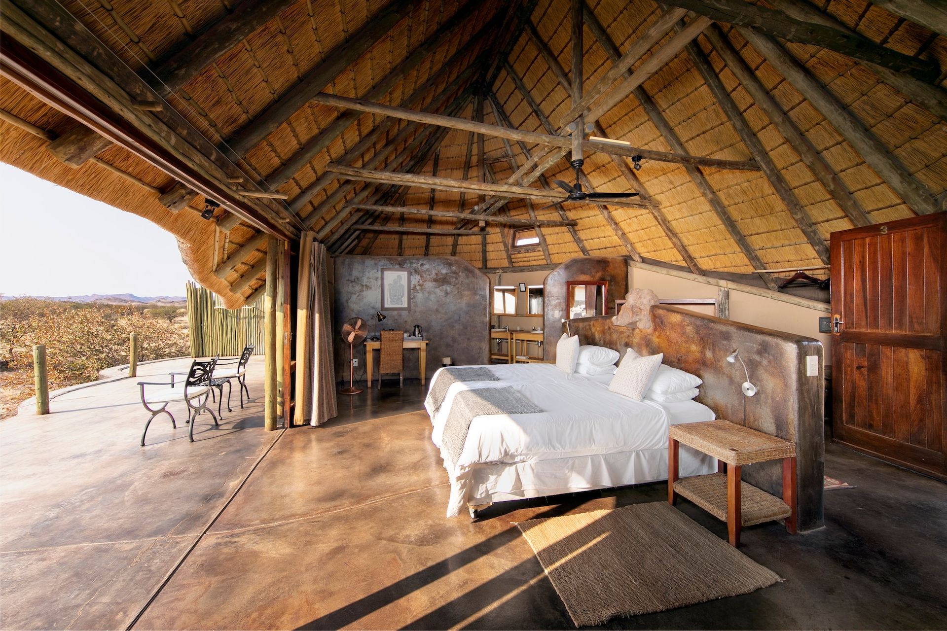 A bedroom with a king size bed and a thatched roof.