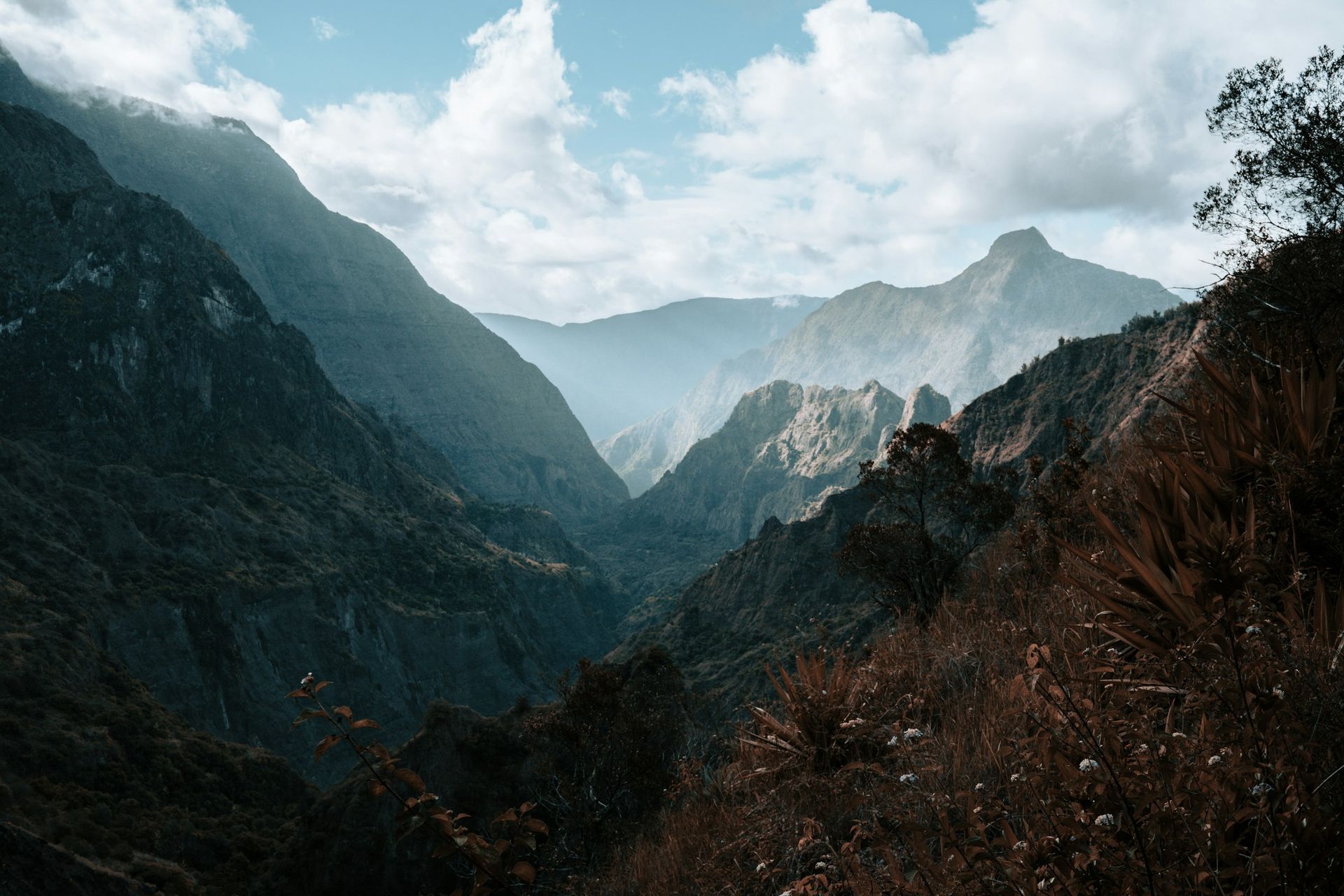 A view of a valley surrounded by mountains on a cloudy day.