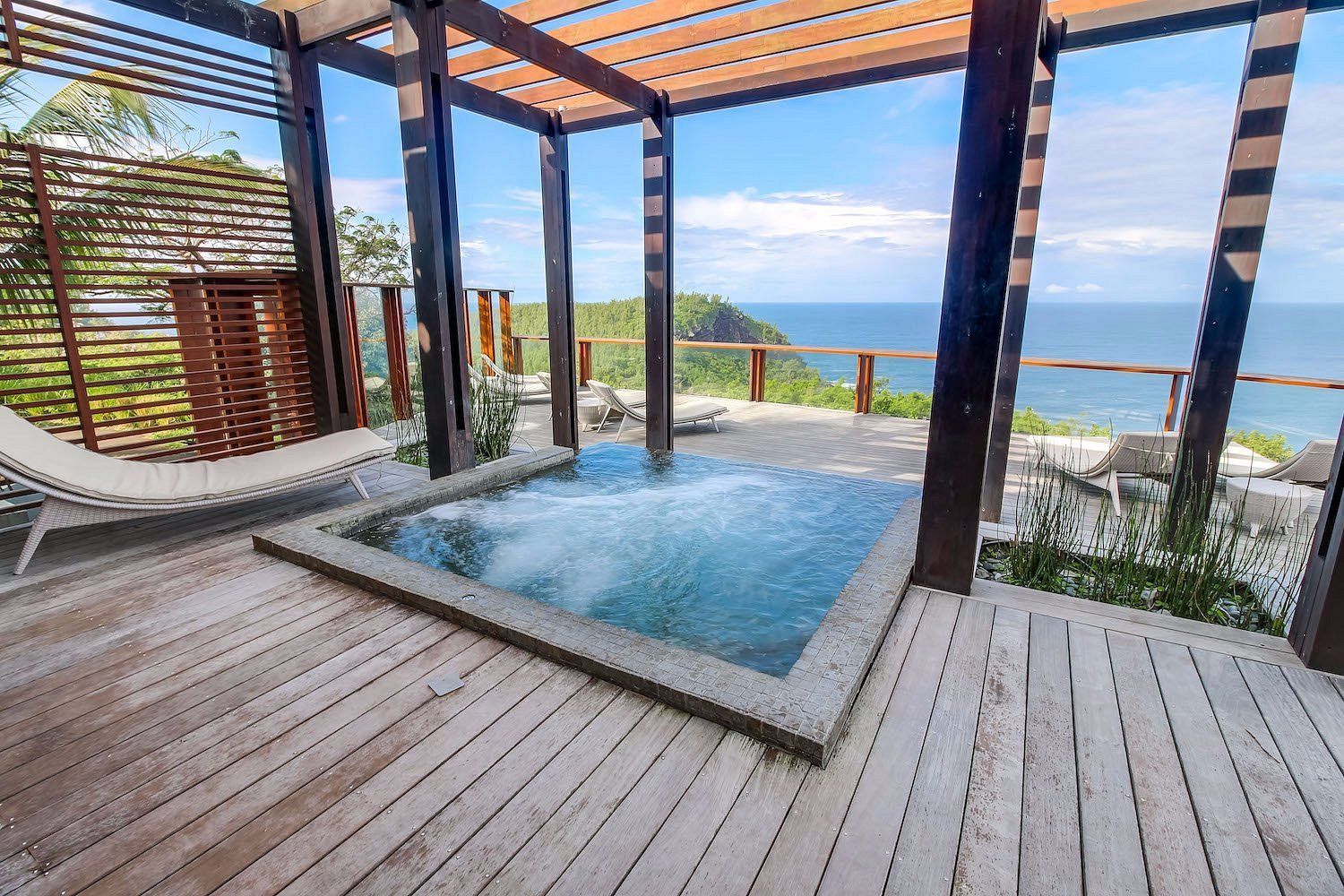 There is a hot tub on the deck with a view of the ocean.