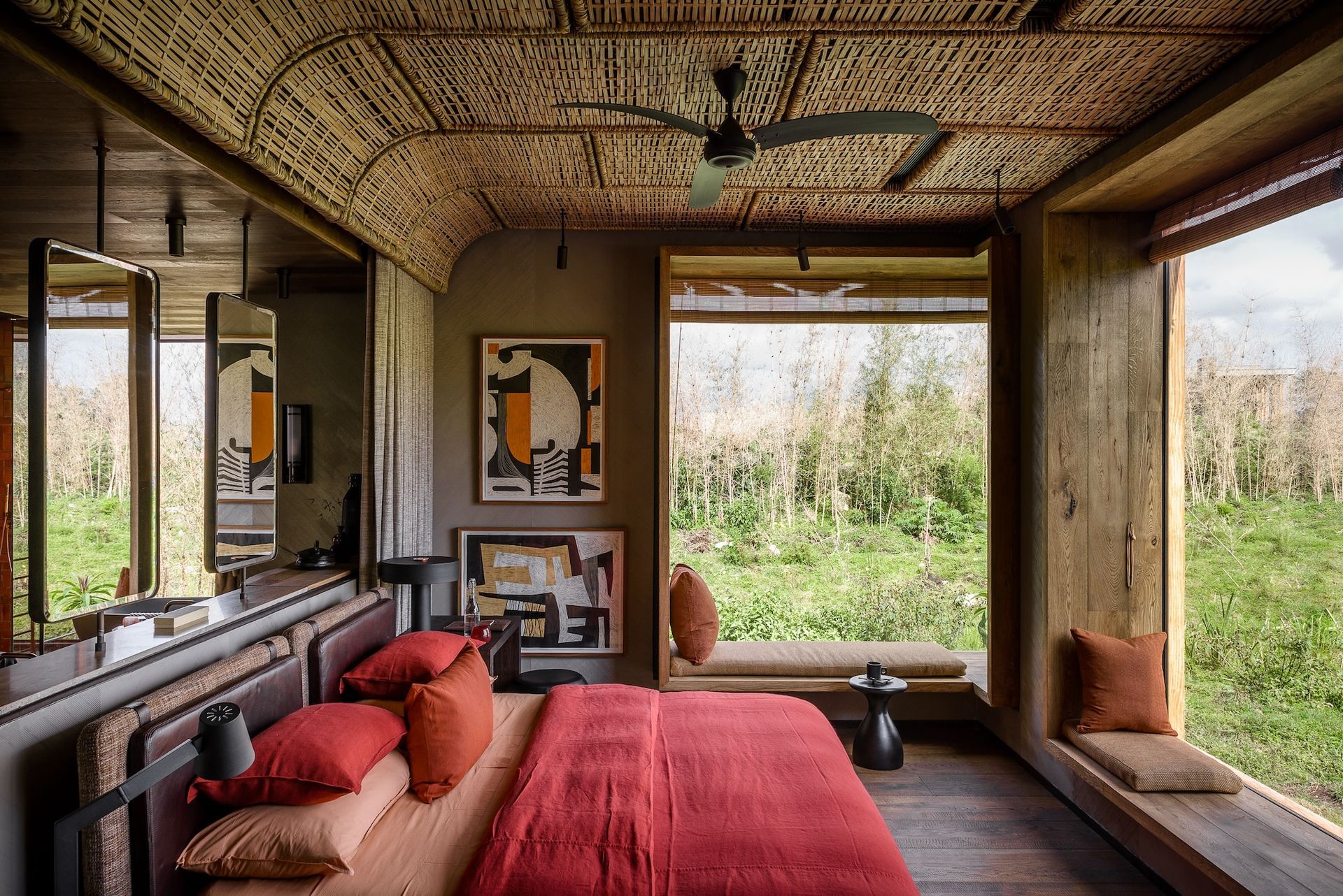 A bedroom with a red bed and a ceiling fan.