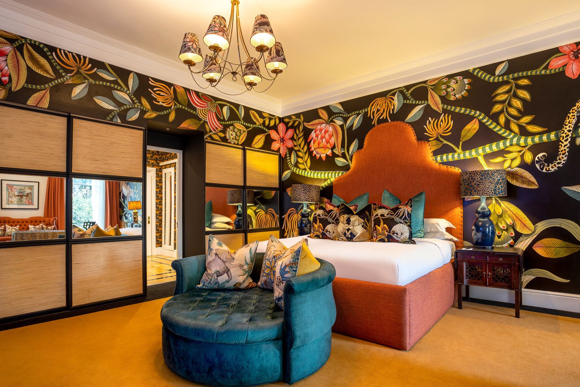 A bedroom with a bed , chair , nightstand and chandelier.