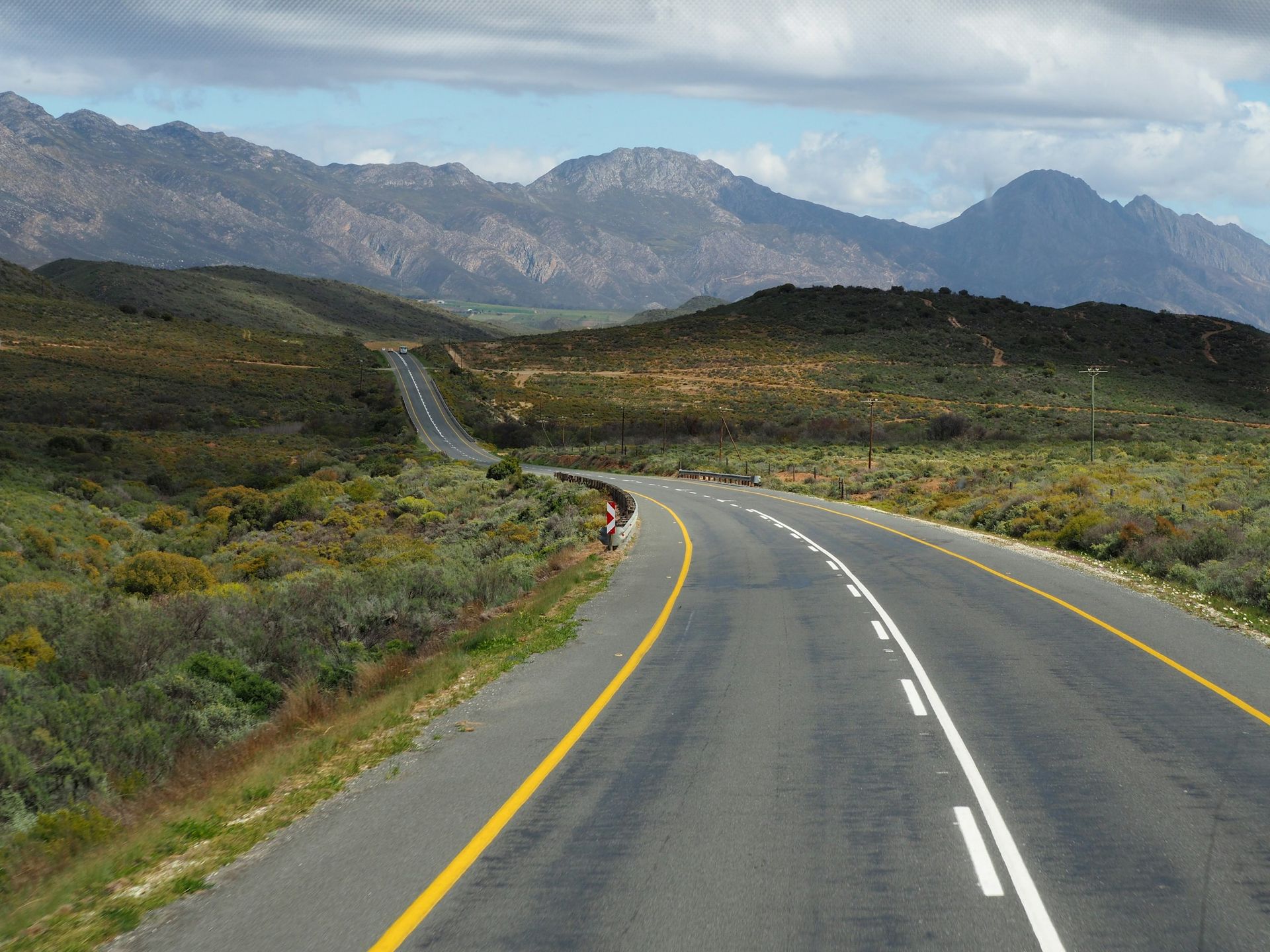 A road going through a mountainous area with mountains in the background