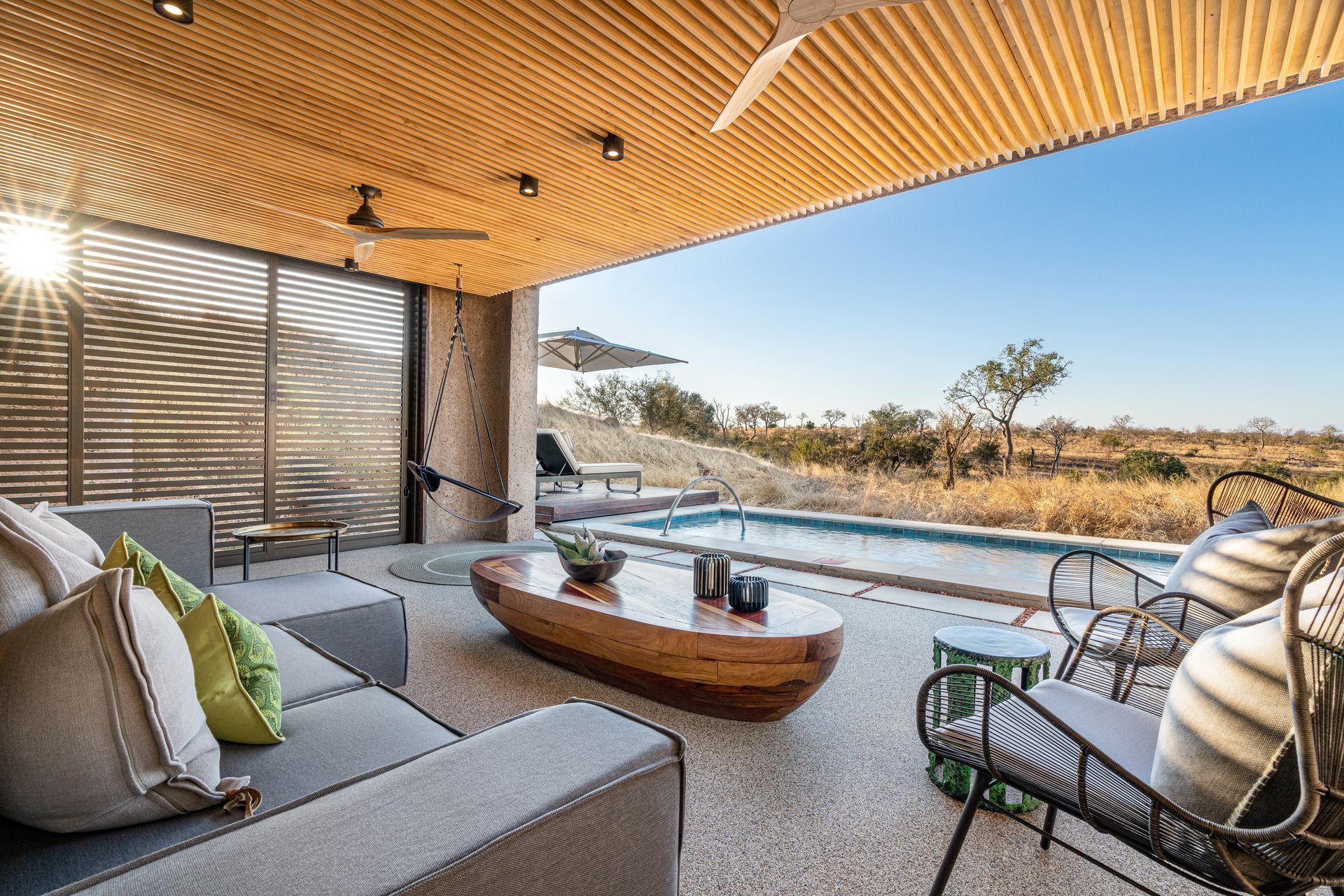 A living room with a couch , table , chairs and a swimming pool.
