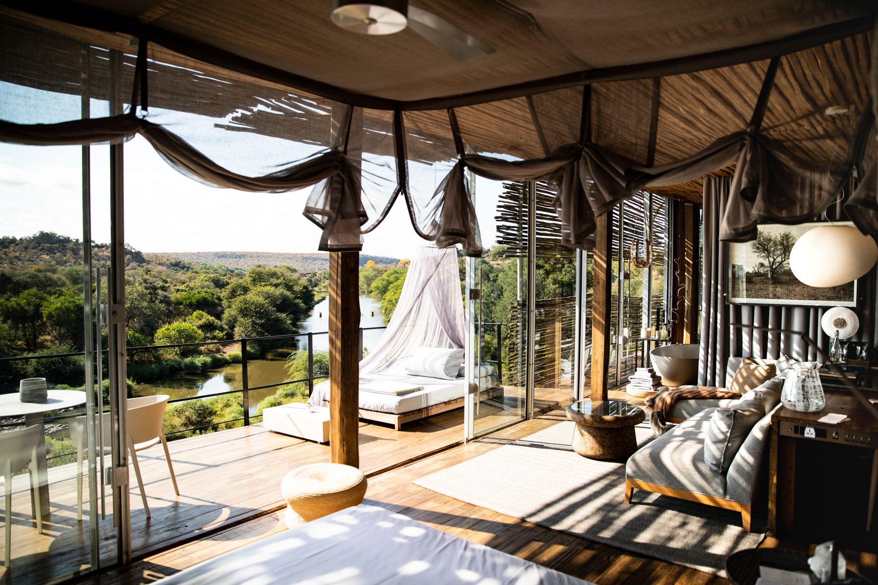 A living room with a lot of windows and a view of a forest.