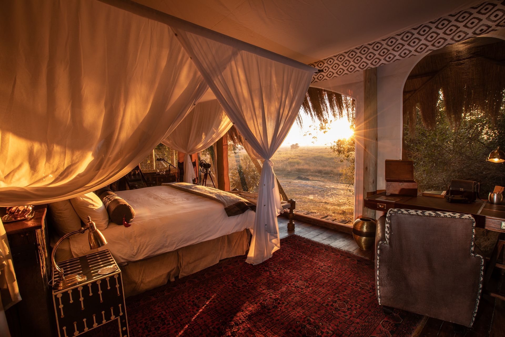 A bedroom with a canopy bed and a large window.